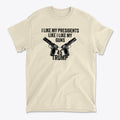 I Like My Presidents Like I Like My Guns 45 Trump graphic on a beige t-shirt with gun illustrations.