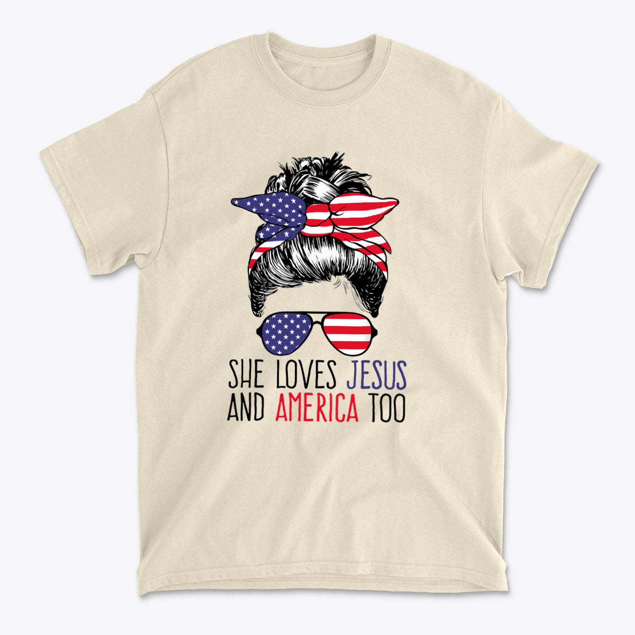A beige t-shirt featuring a graphic design with the phrase 'She Loves Jesus And America Too' and a woman with American flag accessories.