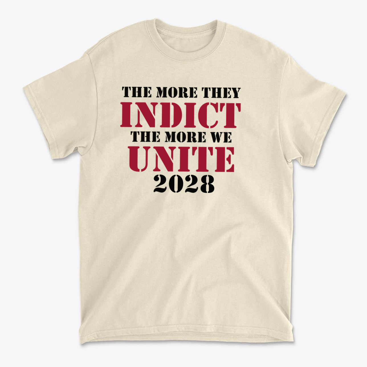 The More They Indict The More We Unite 2028 Blk Ltrs t-shirt featuring bold text on a cream background.