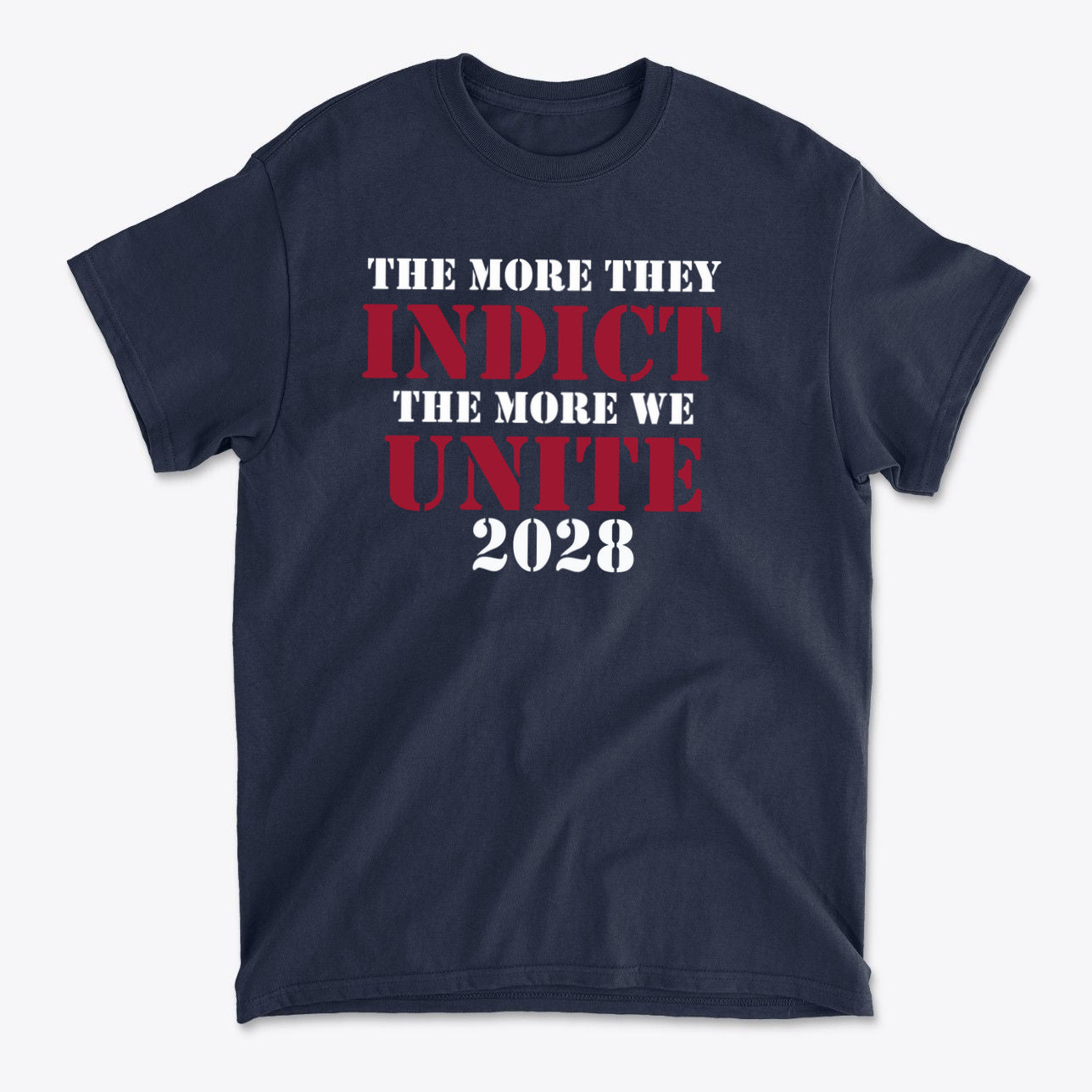 The More They Indict The More We Unite 2028 Wht Ltrs graphic T-shirt featuring bold text in red and white on navy background.