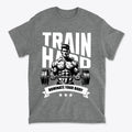 Train Hard Dominate Your Body Now graphic tee featuring a muscular figure lifting weights.
