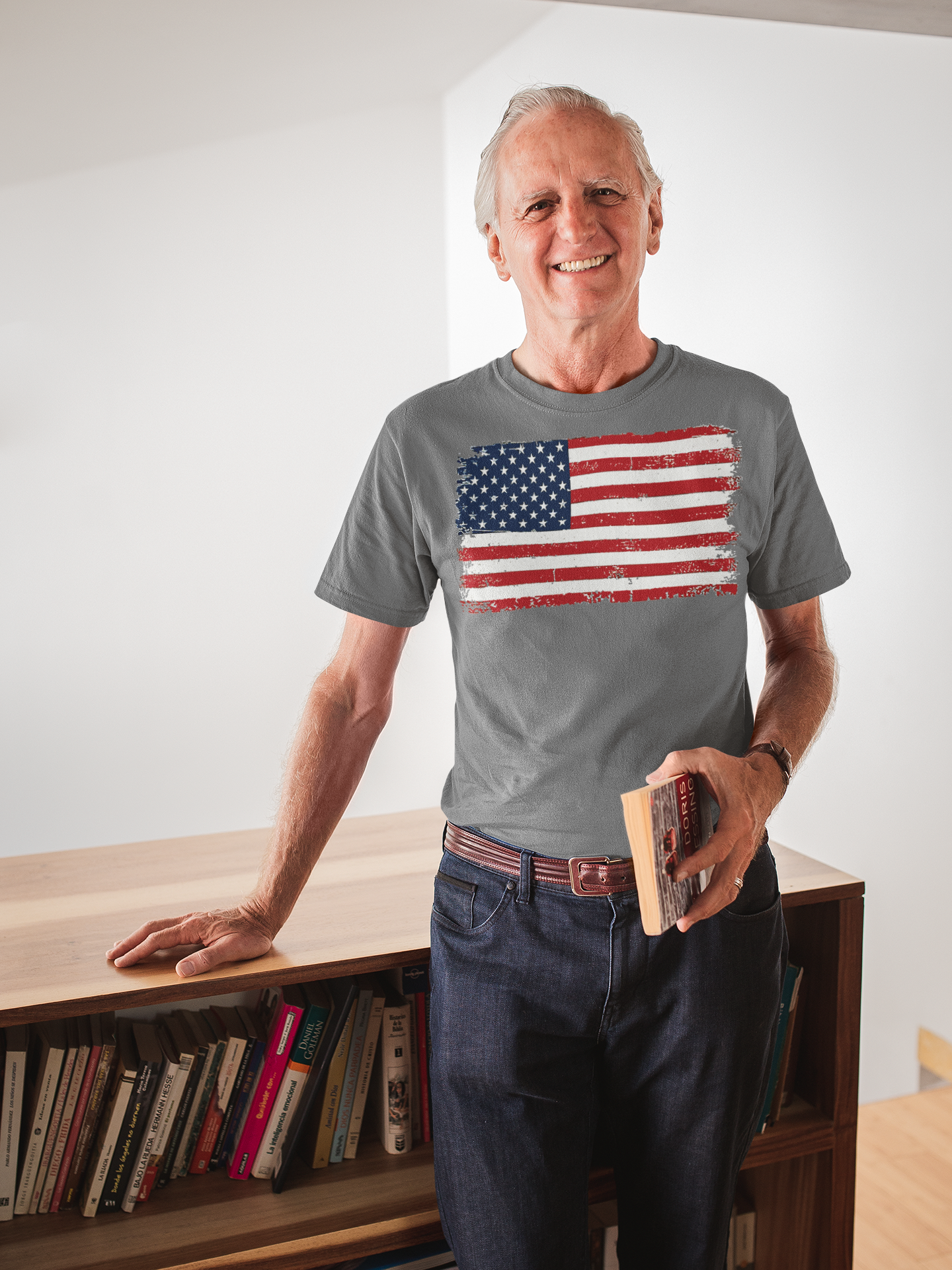 Man wearing a Distressed American Flag Gear Tee, standing near a bookshelf with a smile.