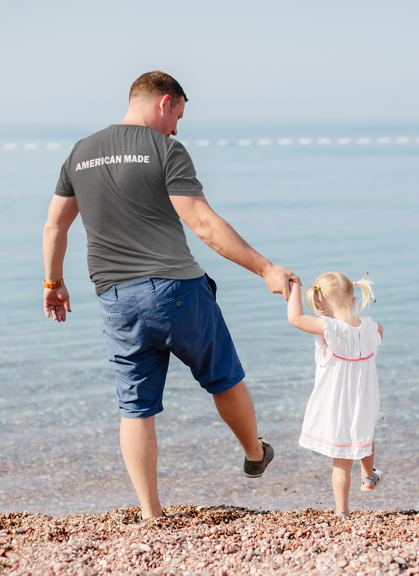Father and daughter on the beach wearing Authentic American Made Apparel, showcasing a conservative message.