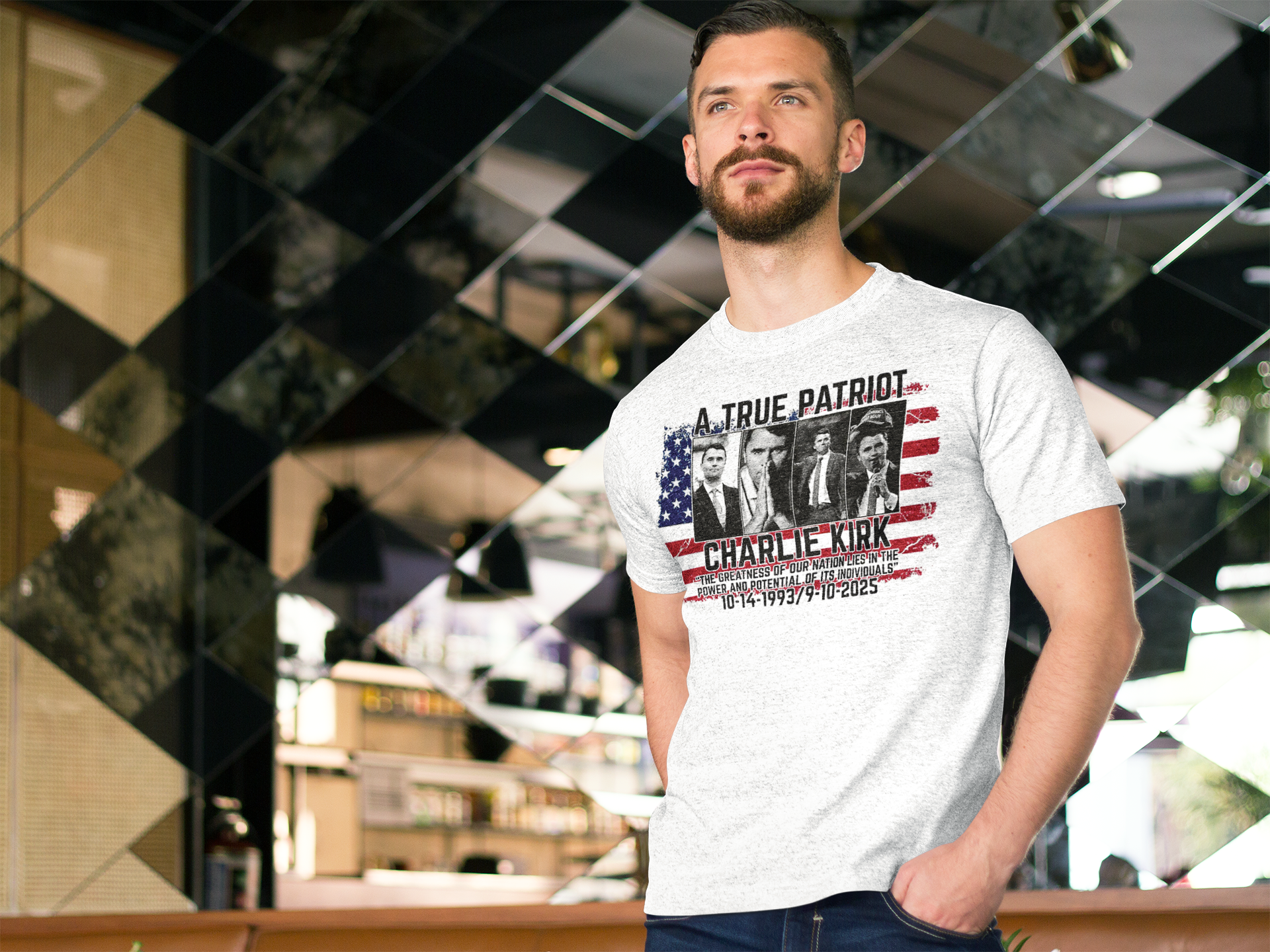 Man wearing a Charlie Kirk A True Patriot Print t-shirt in a stylish cafe setting.