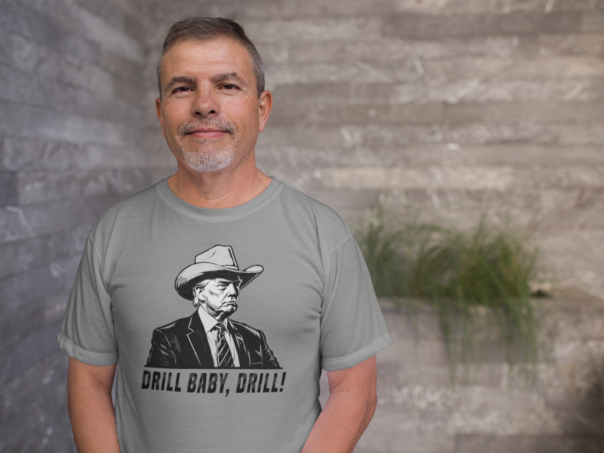 Man wearing a gray shirt with the phrase Drill Baby Drill Patriotic Graphic Tee and a graphic of a cowboy.