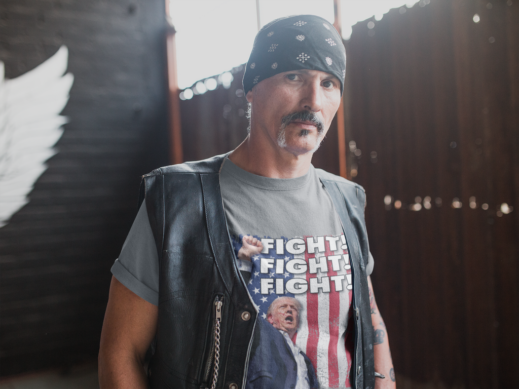 Man wearing a leather vest and a Fight Fight Fight Bold Logo Tee, standing in an industrial space.