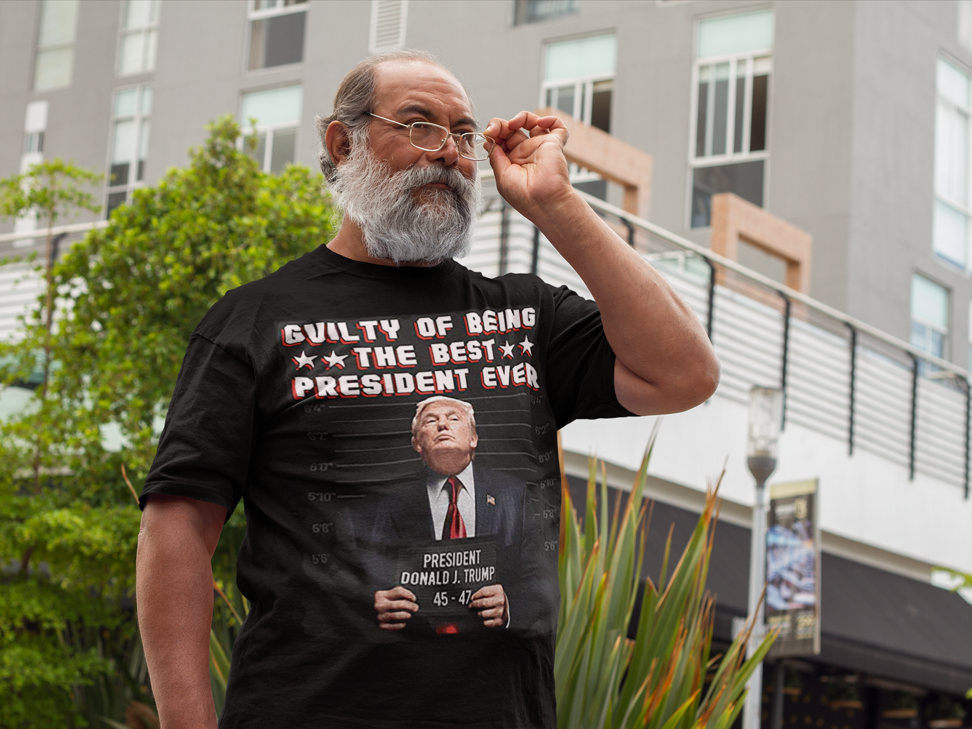 Man wearing a black shirt with the text 'Guilty Of Being The Best President Ever 45 47' in a city setting.