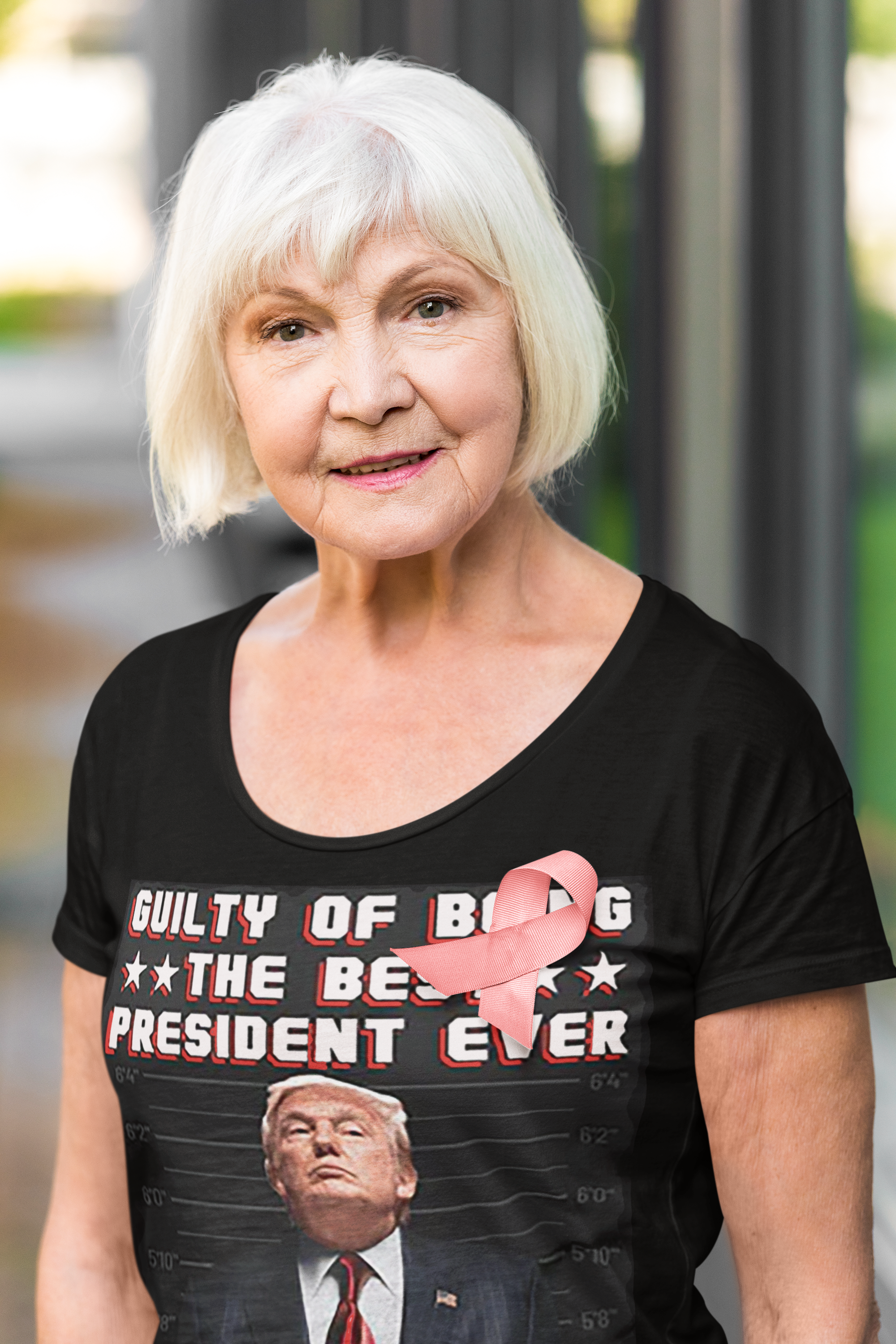 Senior woman wearing a shirt with the phrase 'Guilty Of Being The Best President Ever 45 47' and pink ribbon.