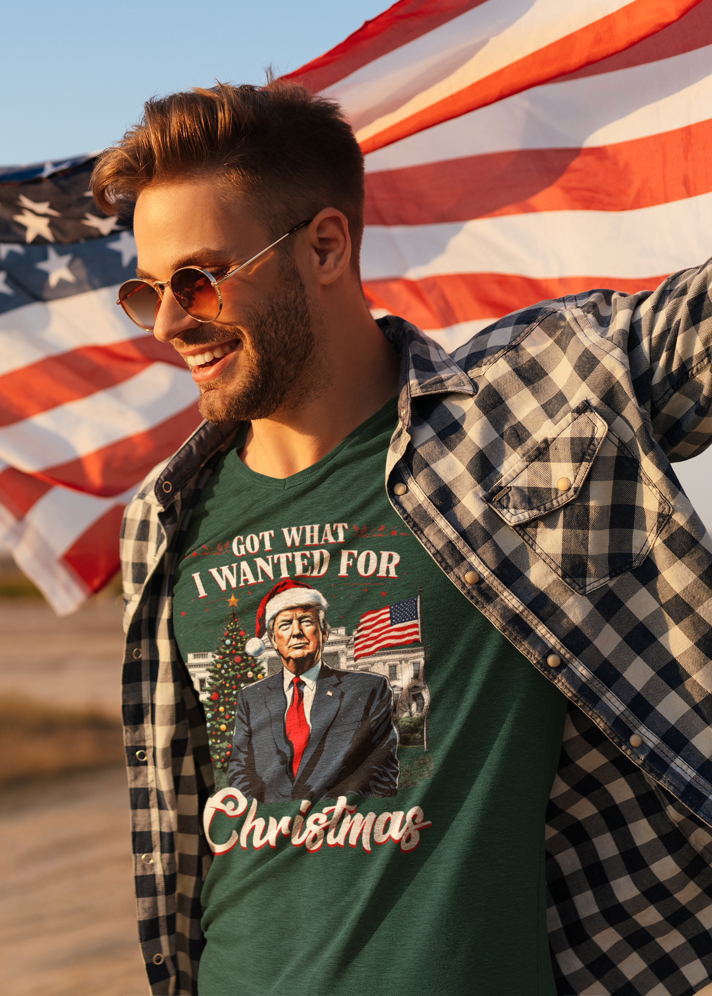 A man wearing a shirt that says I Got What I Wanted For Christmas, smiling and holding an American flag.