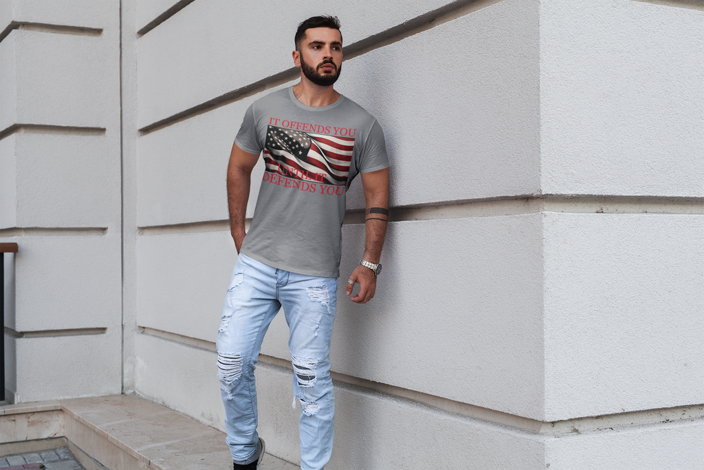 If Offends You Until It Defends You graphic tee with American flag design worn by a man outdoors.