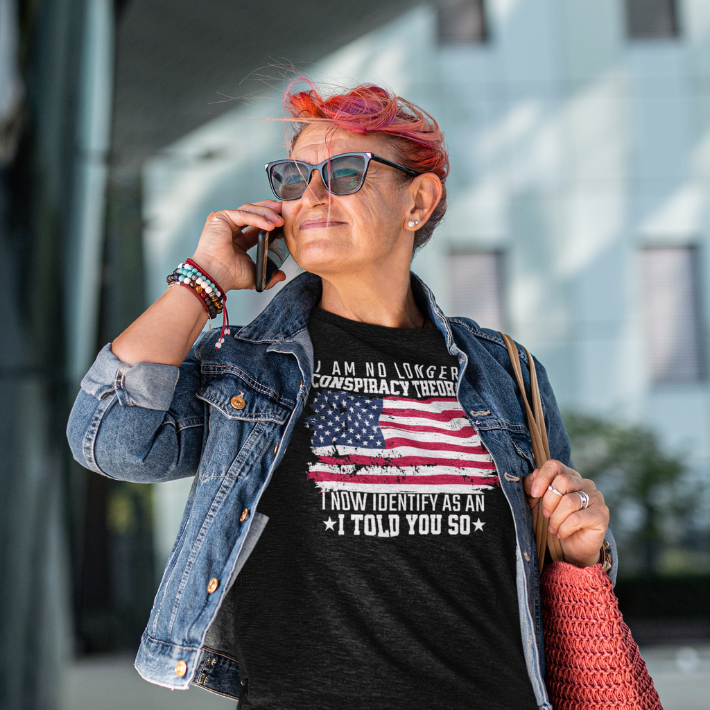 Woman wearing I Am No Longer A Conspiracy Theorist shirt while talking on the phone outdoors.