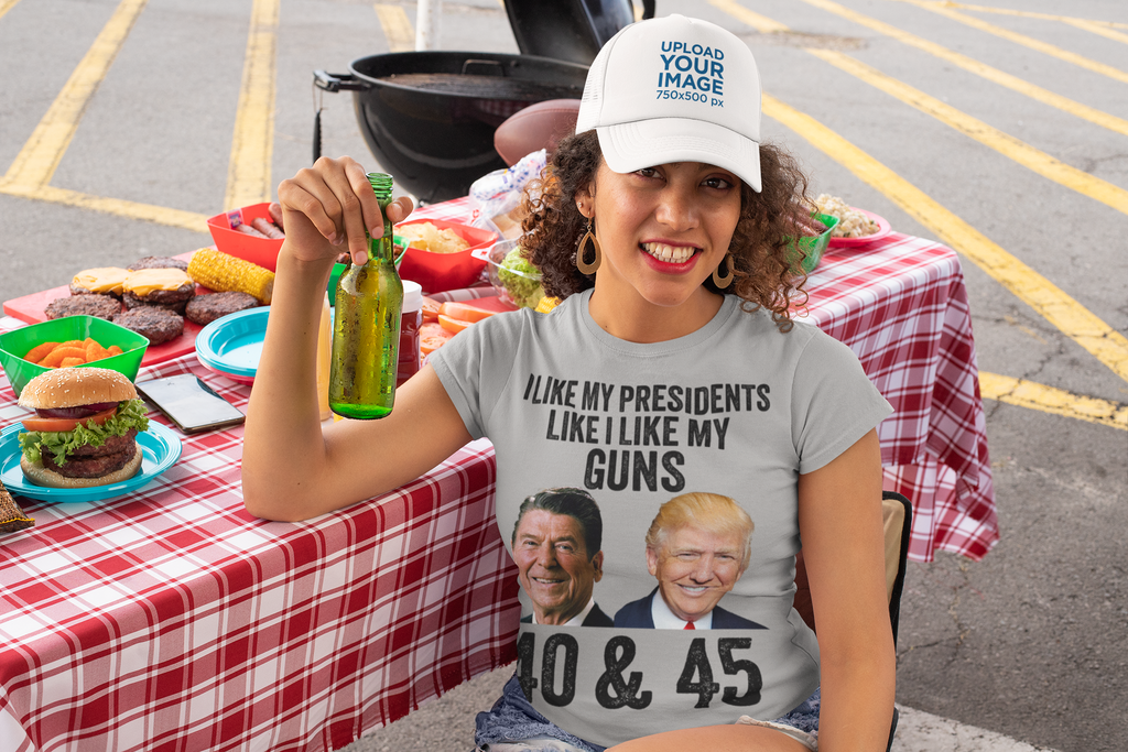 Woman holding a drink, wearing a t-shirt saying I Like My Presidents Like I Like My Guns 40 & 45 at a barbecue.