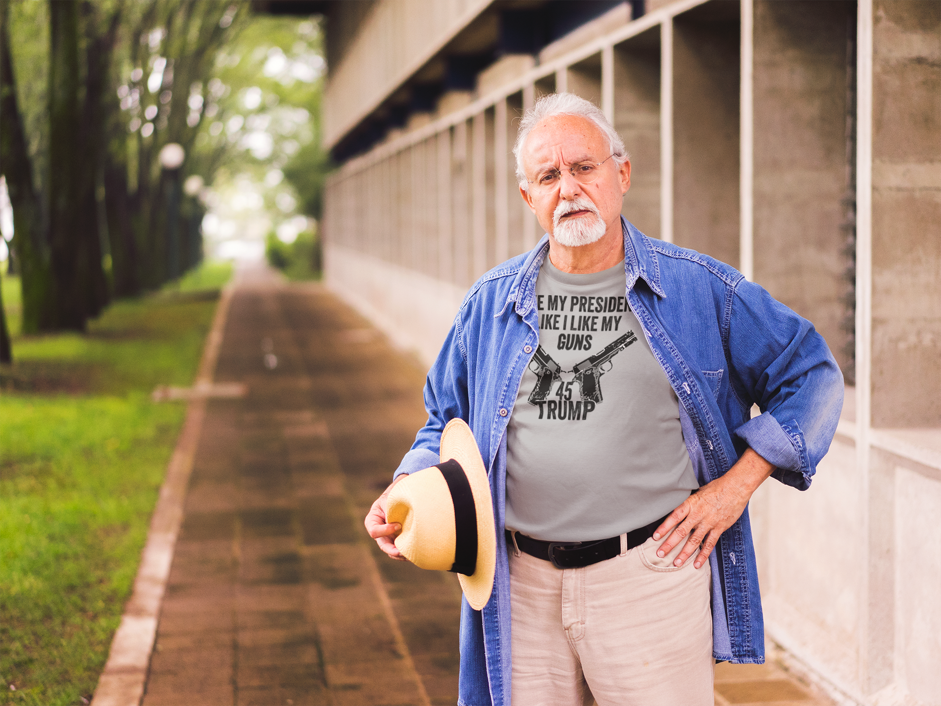 An older man wearing a shirt that says I Like My Presidents Like I Like My Guns 45 Trump in an outdoor setting.