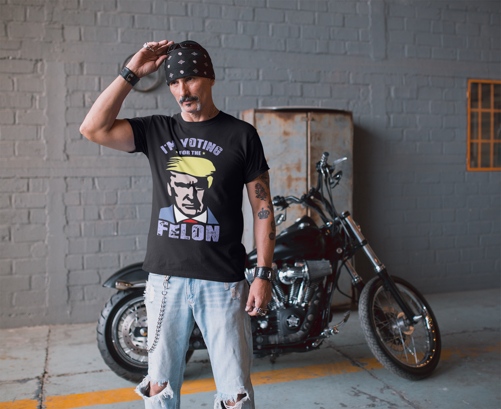 Man wearing the Voting For The Felon Proud Tee next to a motorcycle, expressing strong political beliefs.