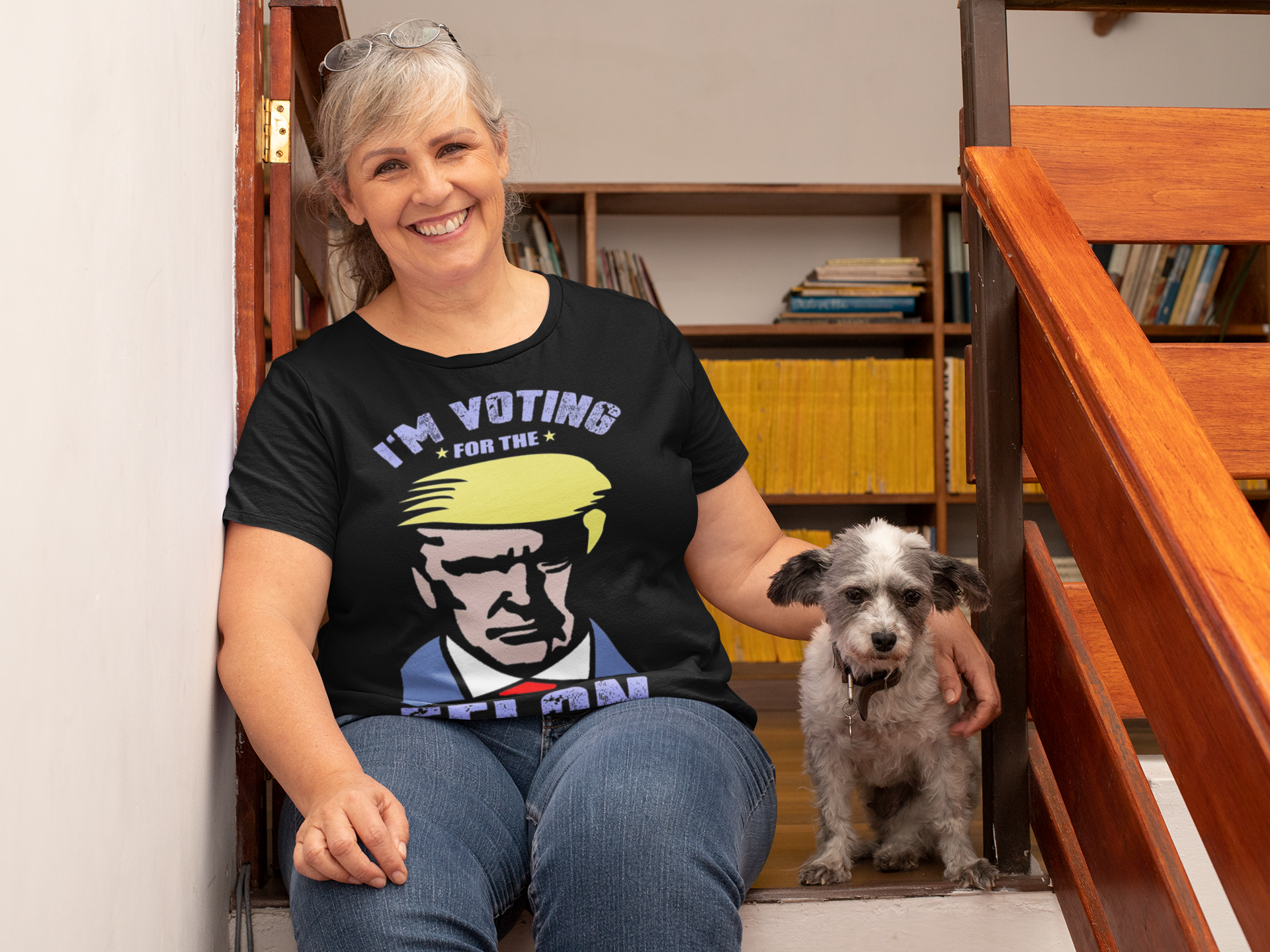 Woman smiling while wearing a Voting For The Felon Proud Tee, sitting with a dog on stairs.