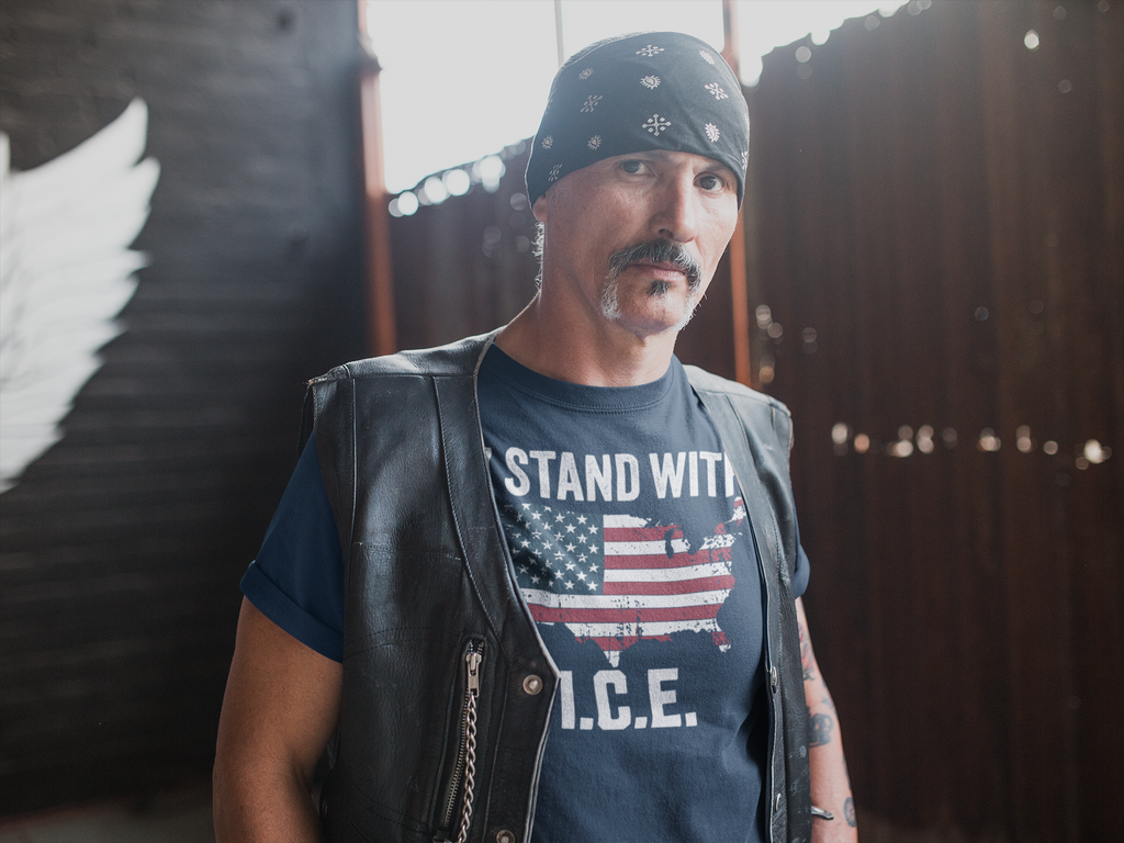 Man wearing a 'Why I Stand With ICE Every Day' t-shirt with an American flag design, posing confidently.