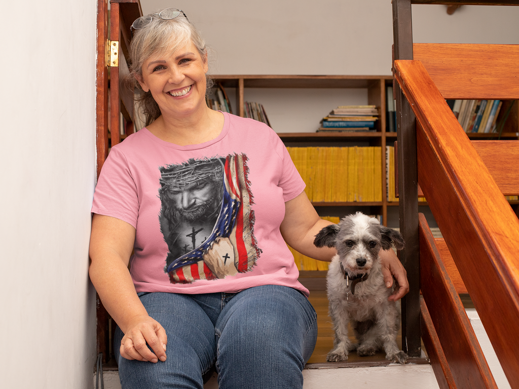 Woman wearing Jesus in American Flag Faith Shirt sitting with dog on stairs, showcasing faith and patriotism.