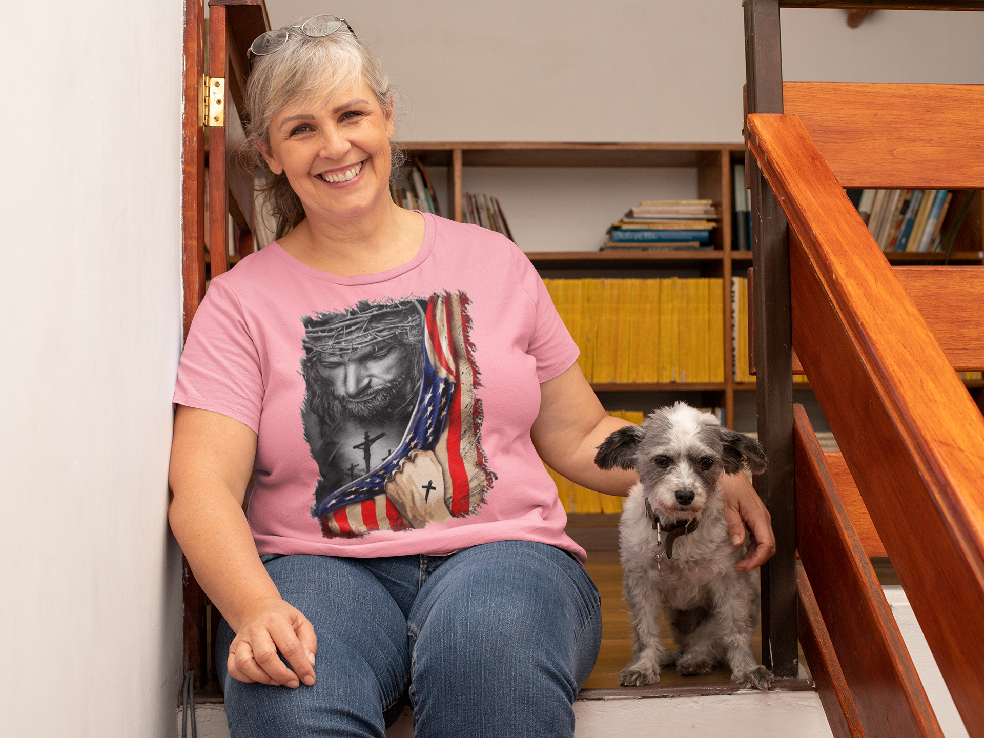 Woman wearing Jesus in American Flag Faith Shirt sitting with dog on stairs, showcasing faith and patriotism.