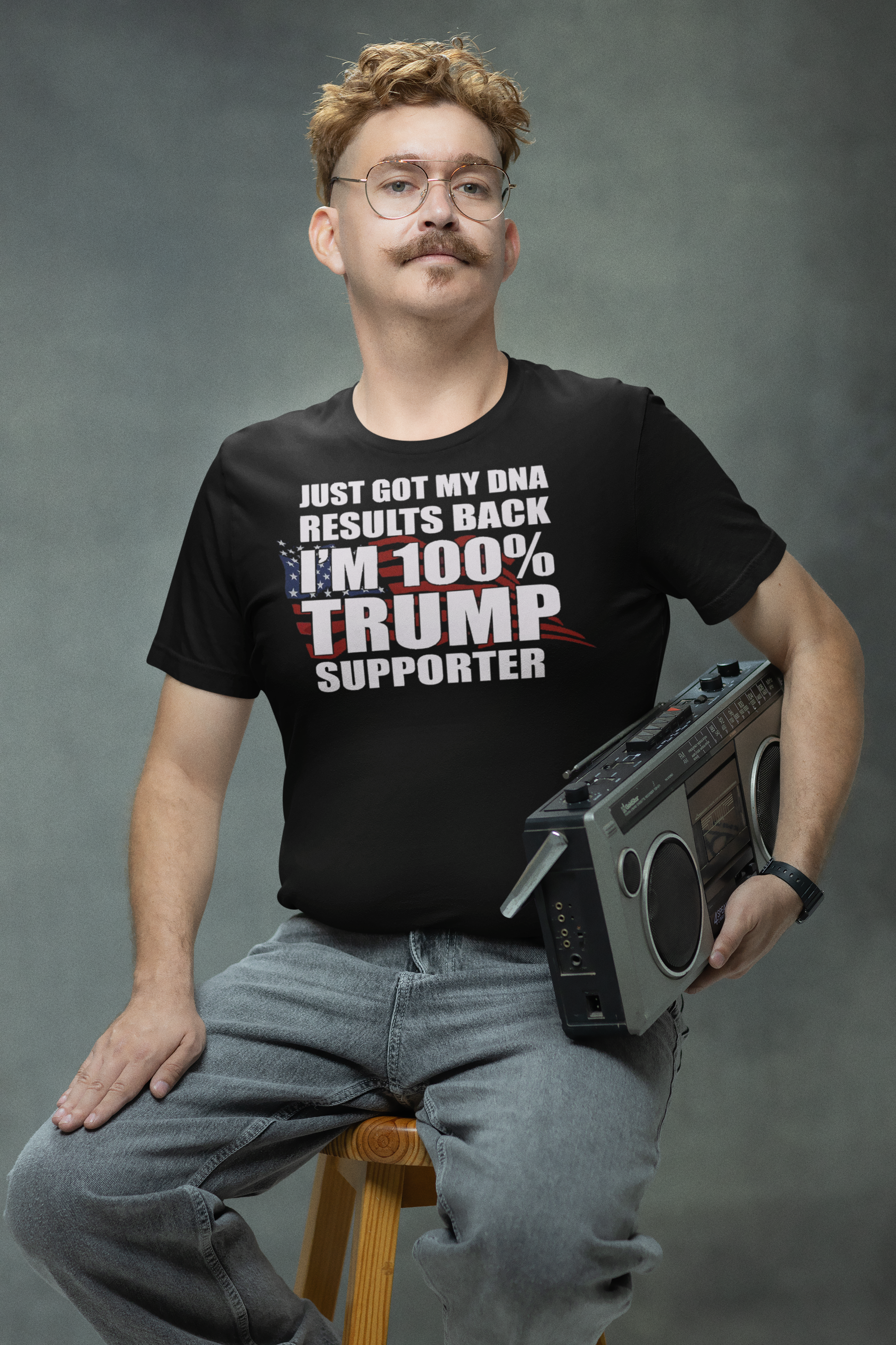 Man wearing 'DNA Results Back I Am One Hundred Percent Trump Supporter' shirt, sitting with boombox.