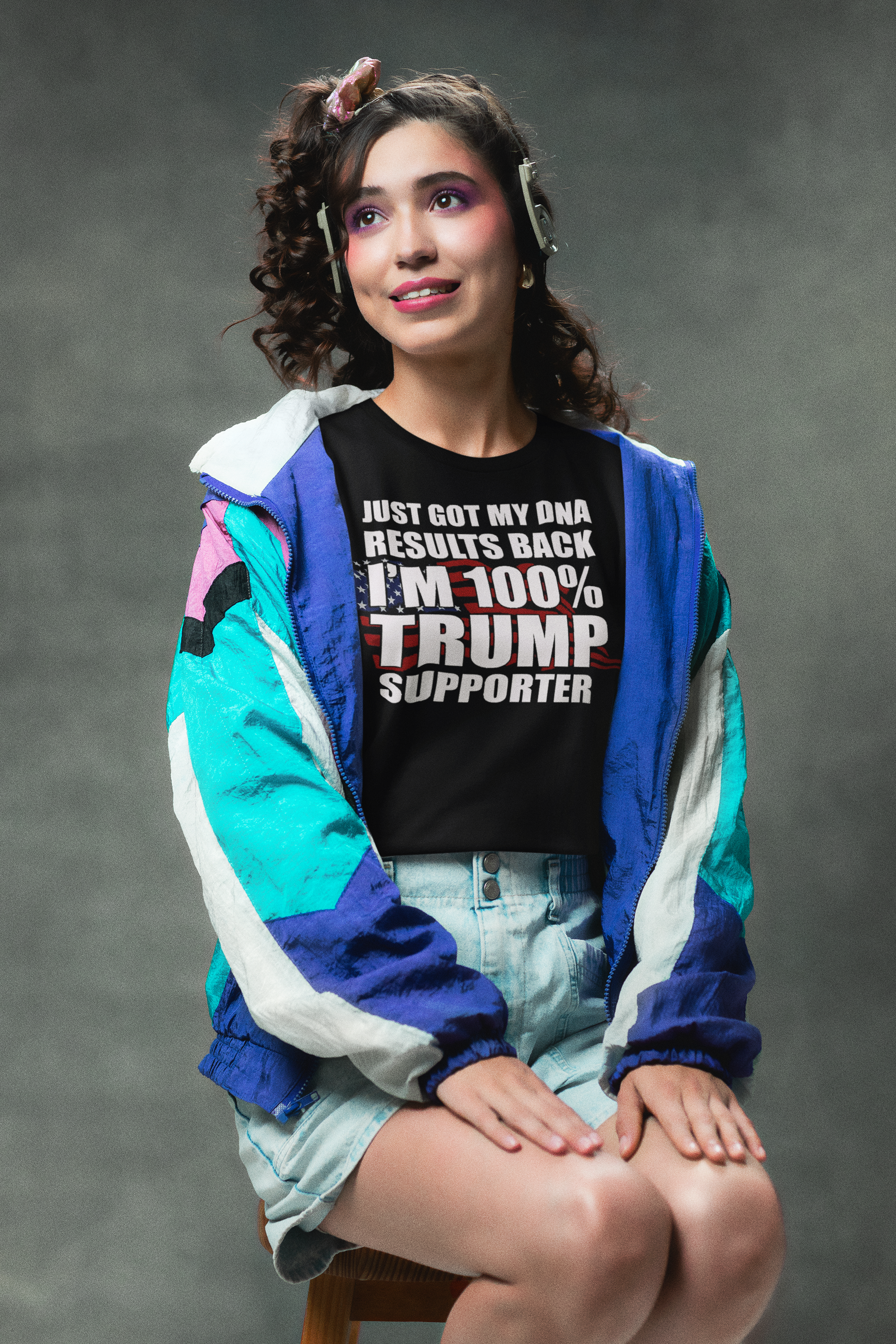 Woman wearing a shirt with the message 'DNA Results Back I Am One Hundred Percent Trump Supporter' and a colorful jacket.
