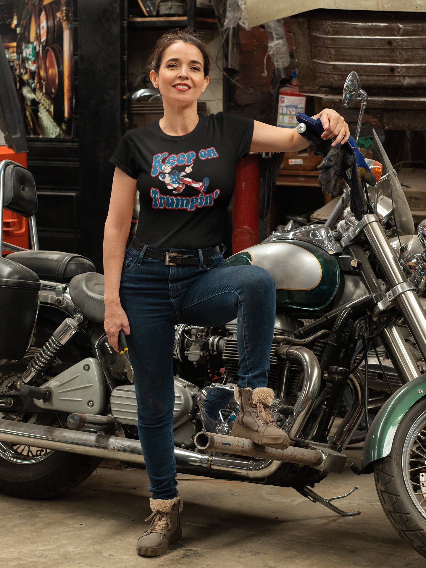Woman in a vintage motorcycle garage wearing a Keep On Trumpin' Vintage Design t-shirt with bold typography.