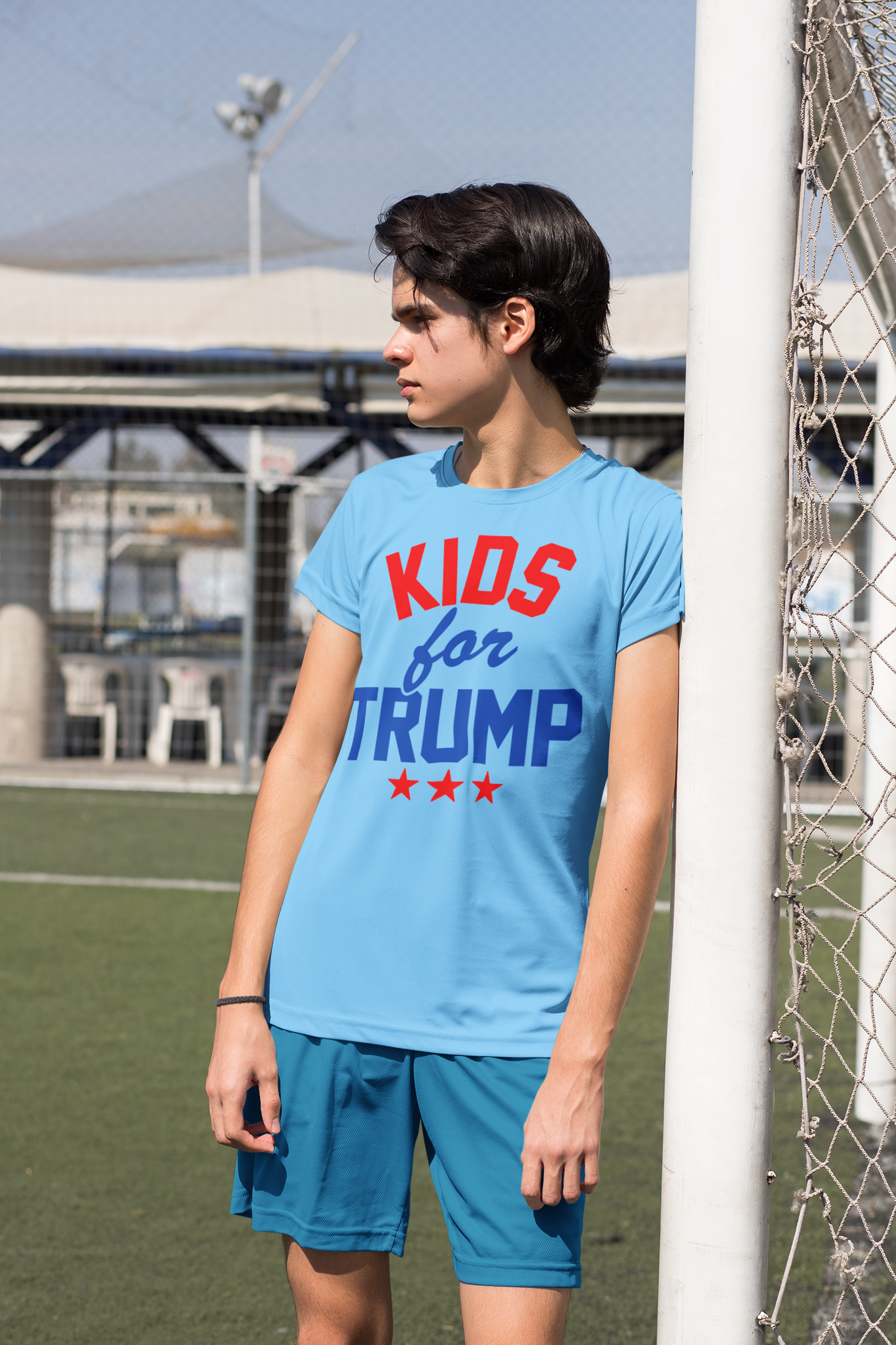 A young person wearing a Kids for Trump USA Pride Shirt, showcasing patriotic colors on a sports field.