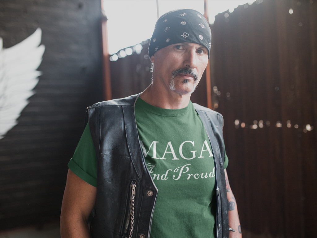 Man wearing MAGA And Proud White Letters Style graphic tee in a rustic setting.