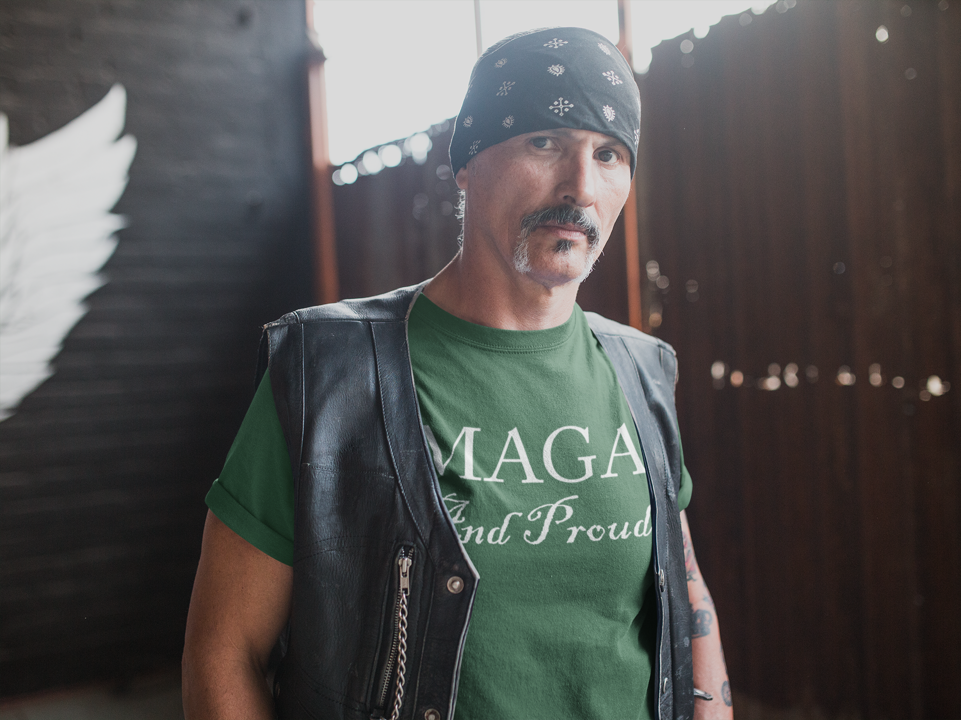 Man wearing MAGA And Proud White Letters Style graphic tee in a rustic setting.