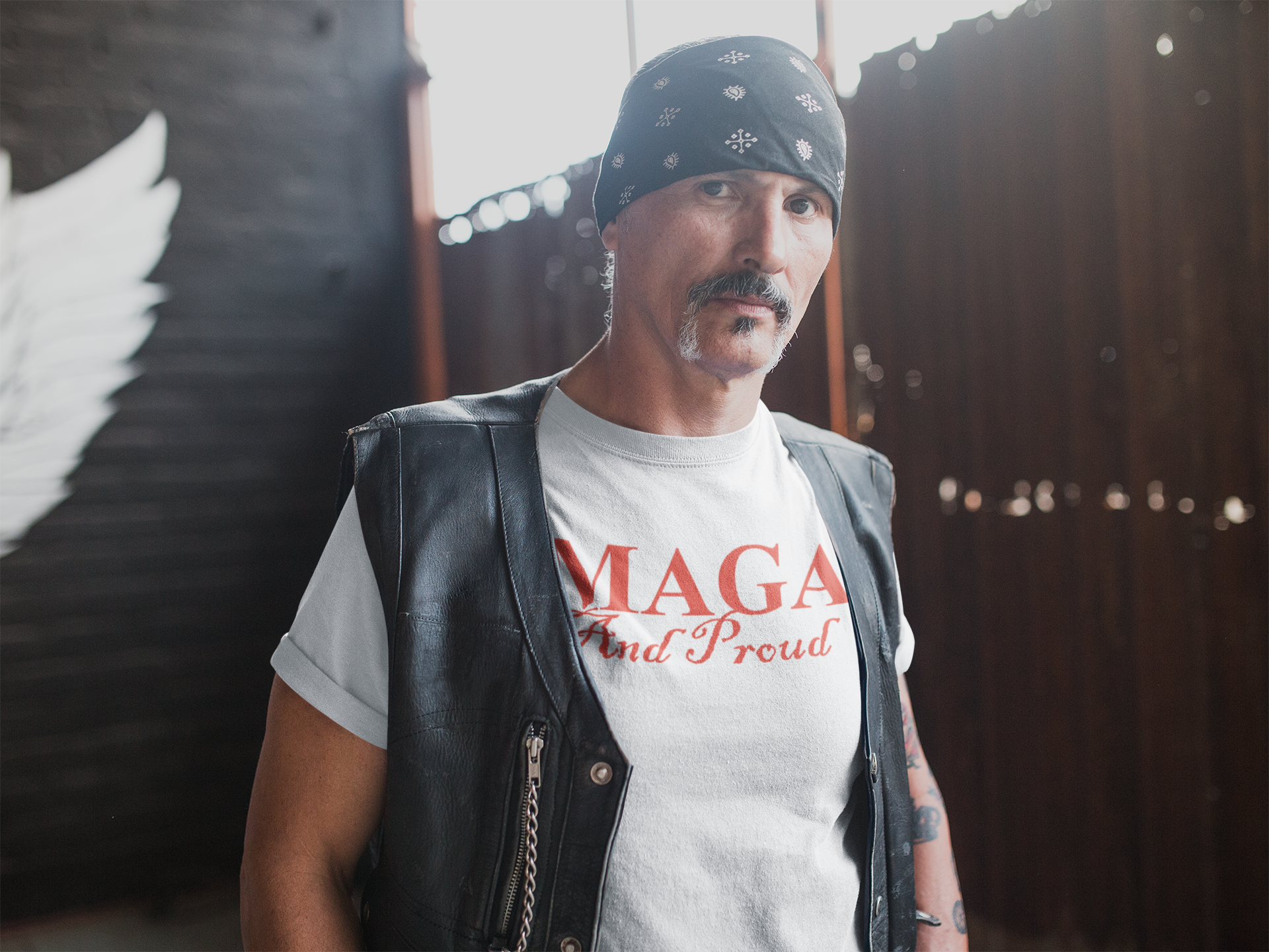 Man wearing MAGA And Proud Red Letters Style graphic tee and leather vest, showcasing personal values and patriotism.