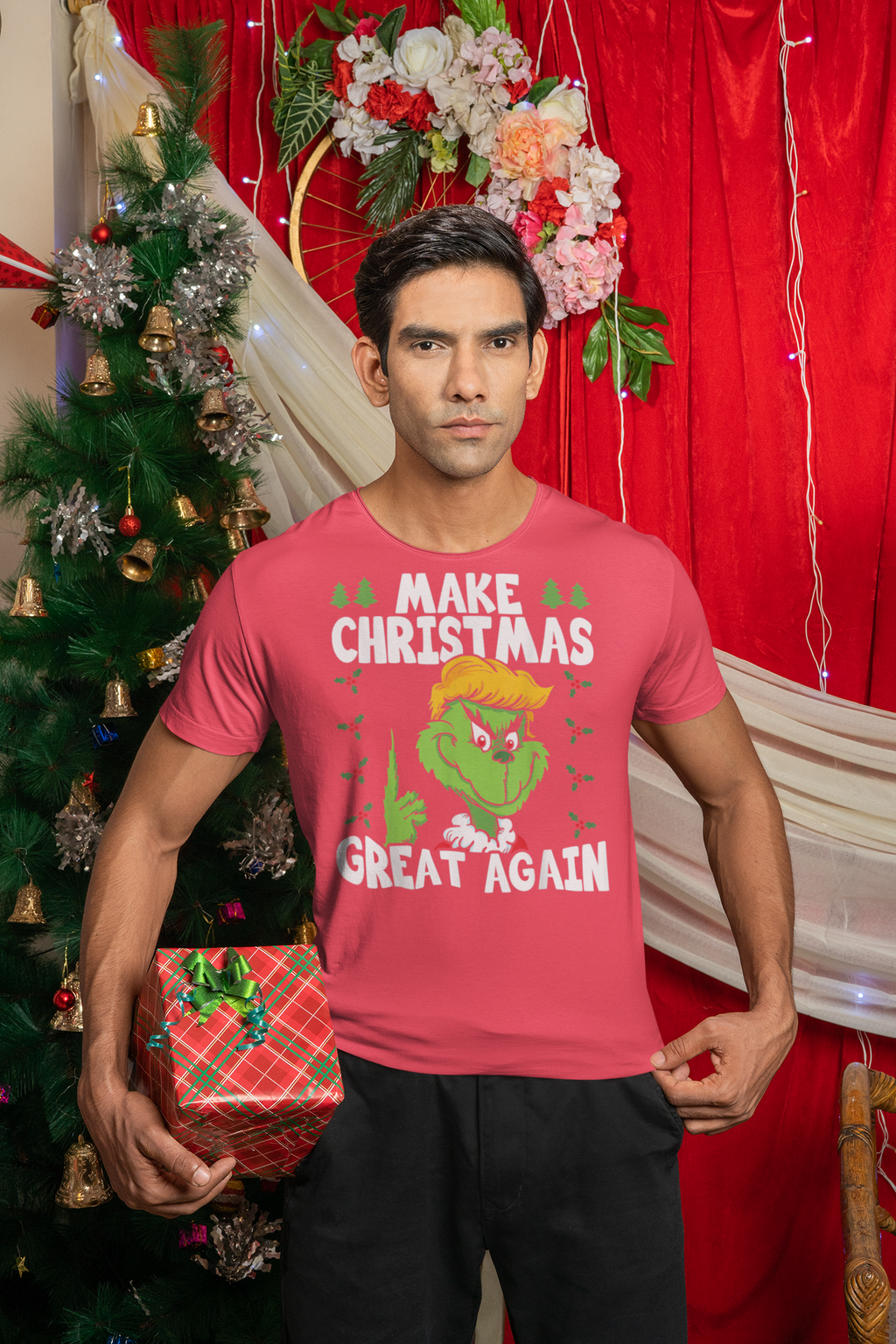 A model wearing a pink t-shirt with the text 'Make Christmas Great Again With The Grinch' in front of a festive backdrop.