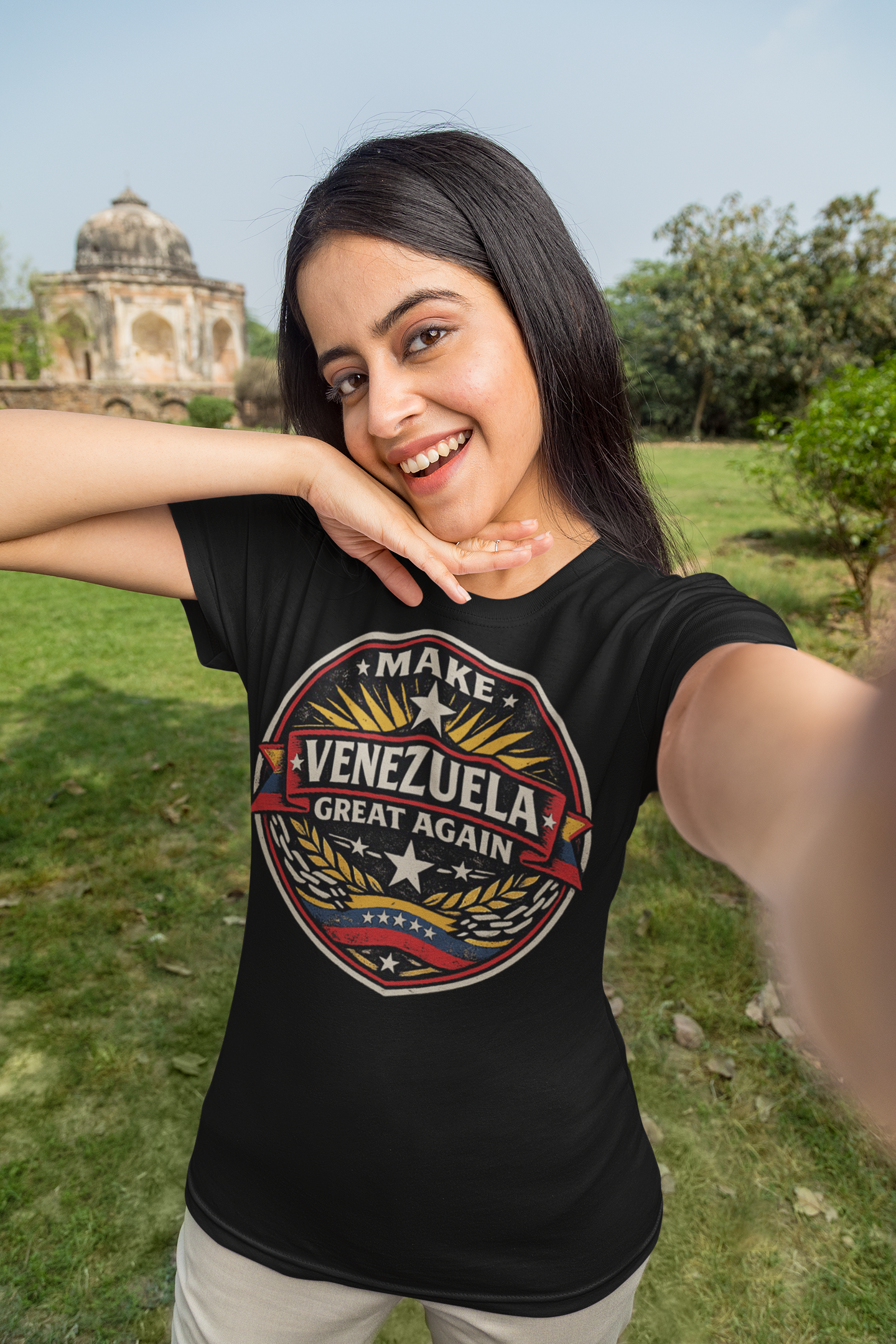 A woman smiling in a black t-shirt with the slogan Make Venezuela Great Again for the Future in a scenic outdoor setting.