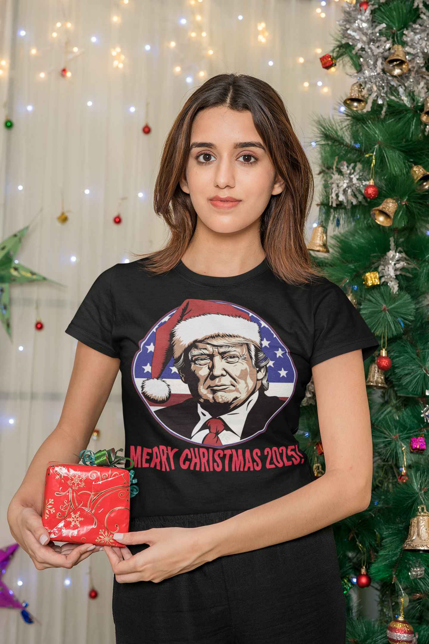Merry Christmas 2025 Trump As Santa graphic t-shirt worn by a woman holding a gift in a holiday setting.