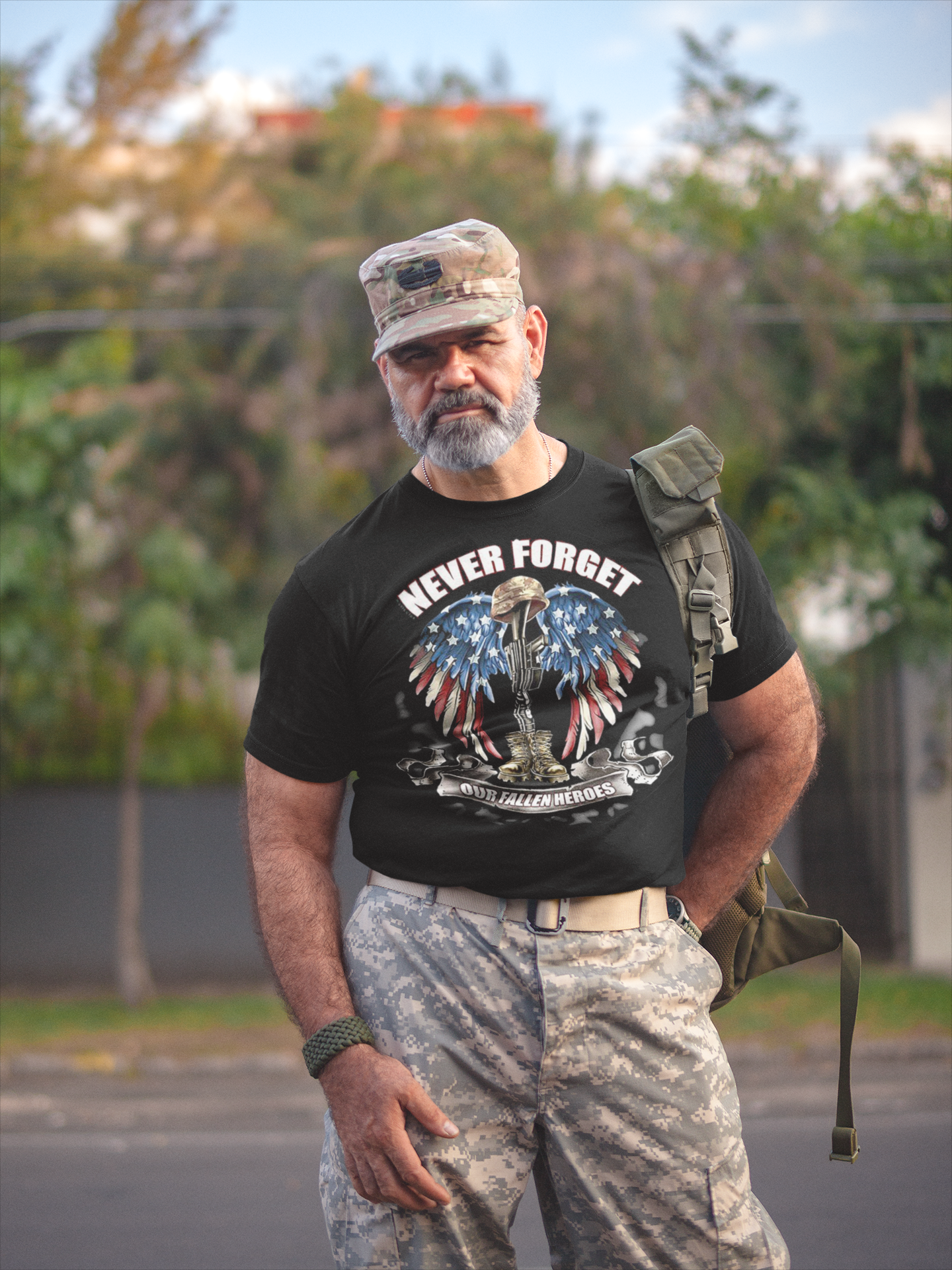 Man in military attire wearing a t-shirt that says 'NEVER FORGET Our Fallen Heroes' while standing outdoors.