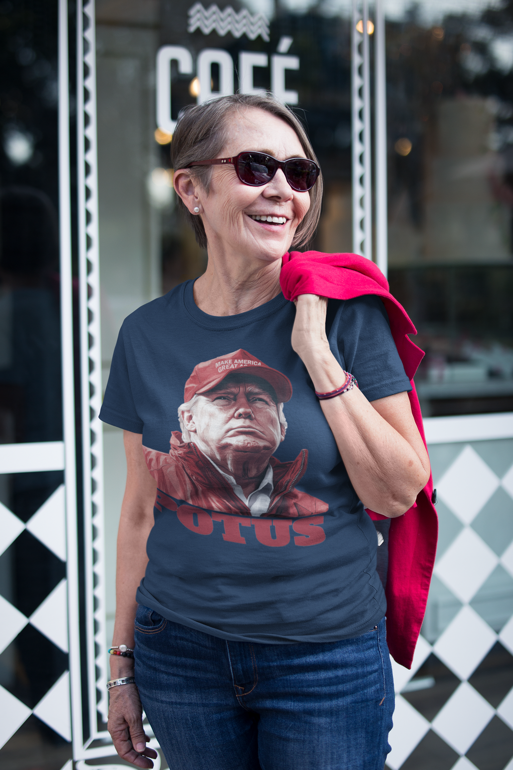Woman wearing POTUS USA Patriotic Apparel Design shirt outside a café, smiling and stylish.