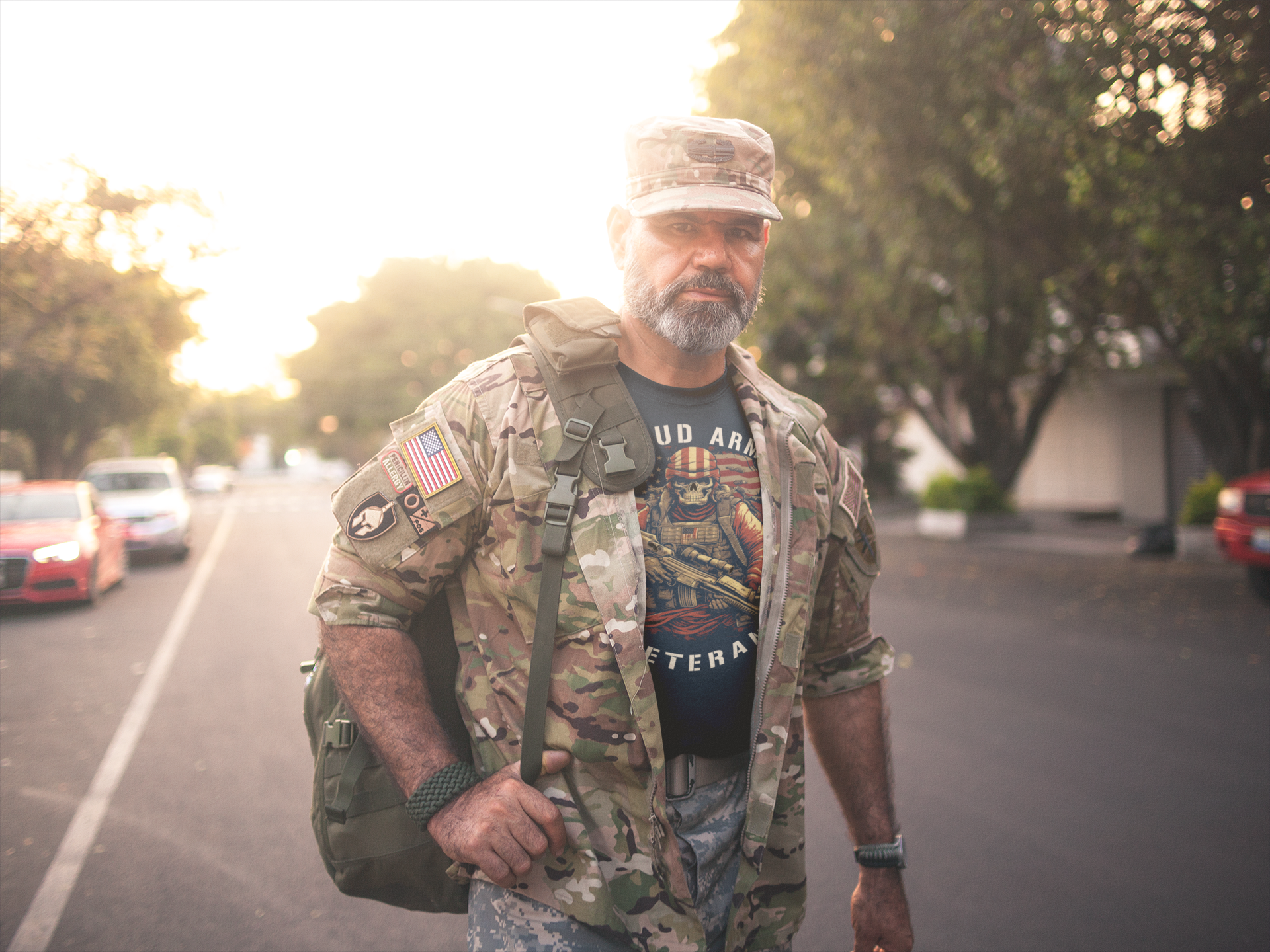 Proud Army Veteran Graphic Tee worn by a soldier in military gear walking down a street at sunset.