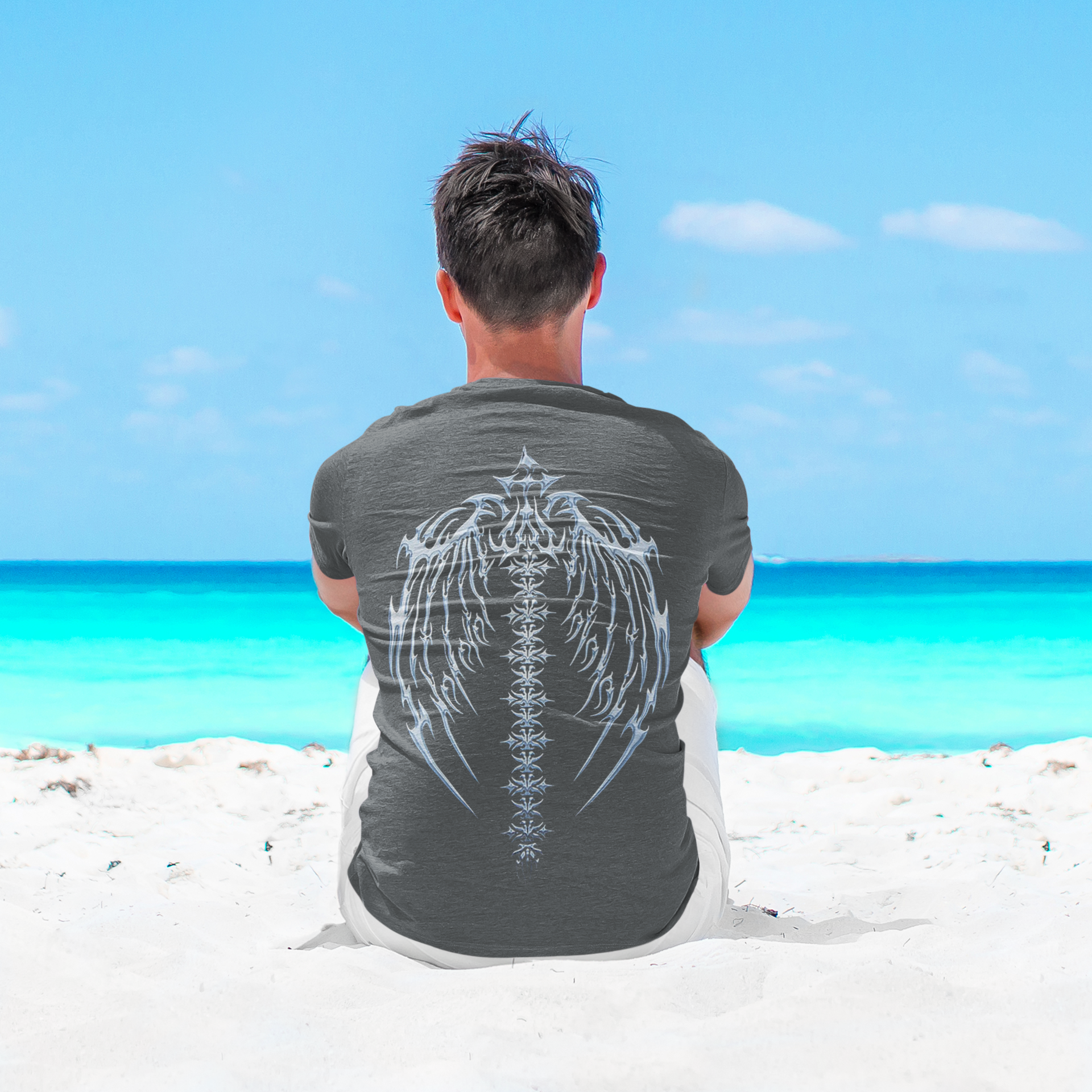 Man sitting on beach wearing Spine Back Design Graphic Print t-shirt with ocean background.