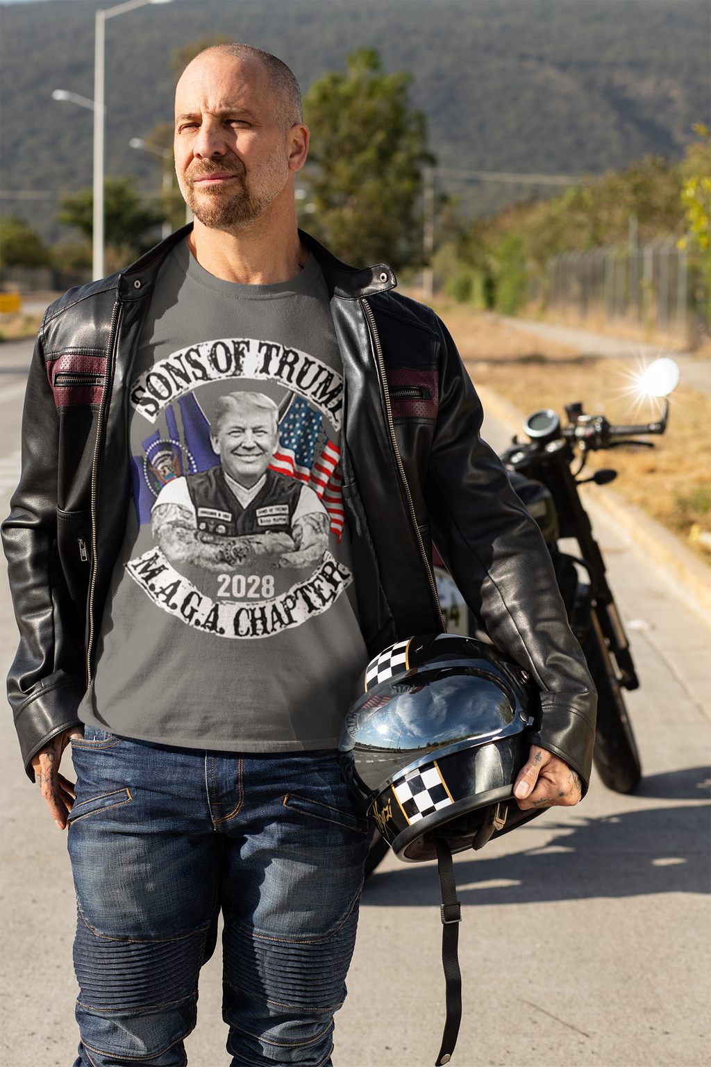 Man wearing Sons Of Trump 2028 M.A.G.A. Chapter graphic t-shirt, standing outdoors next to a motorcycle.