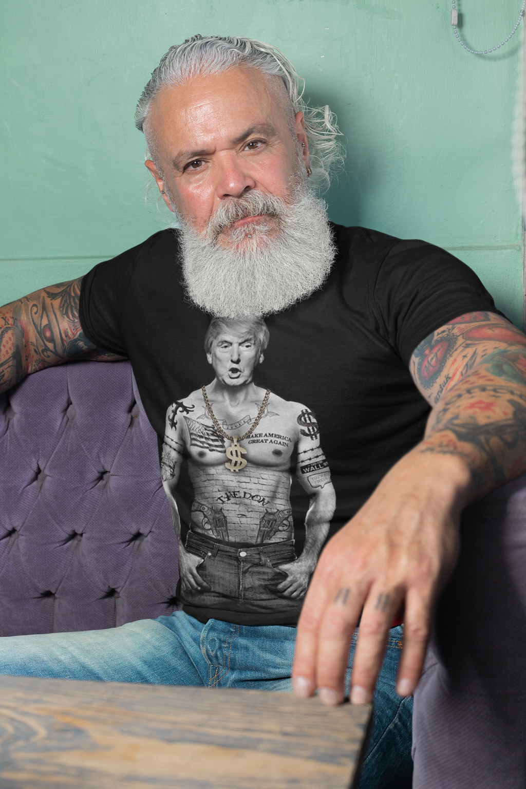 Man wearing a black t-shirt with President Trump Power Pose Art Design sitting on a purple couch.