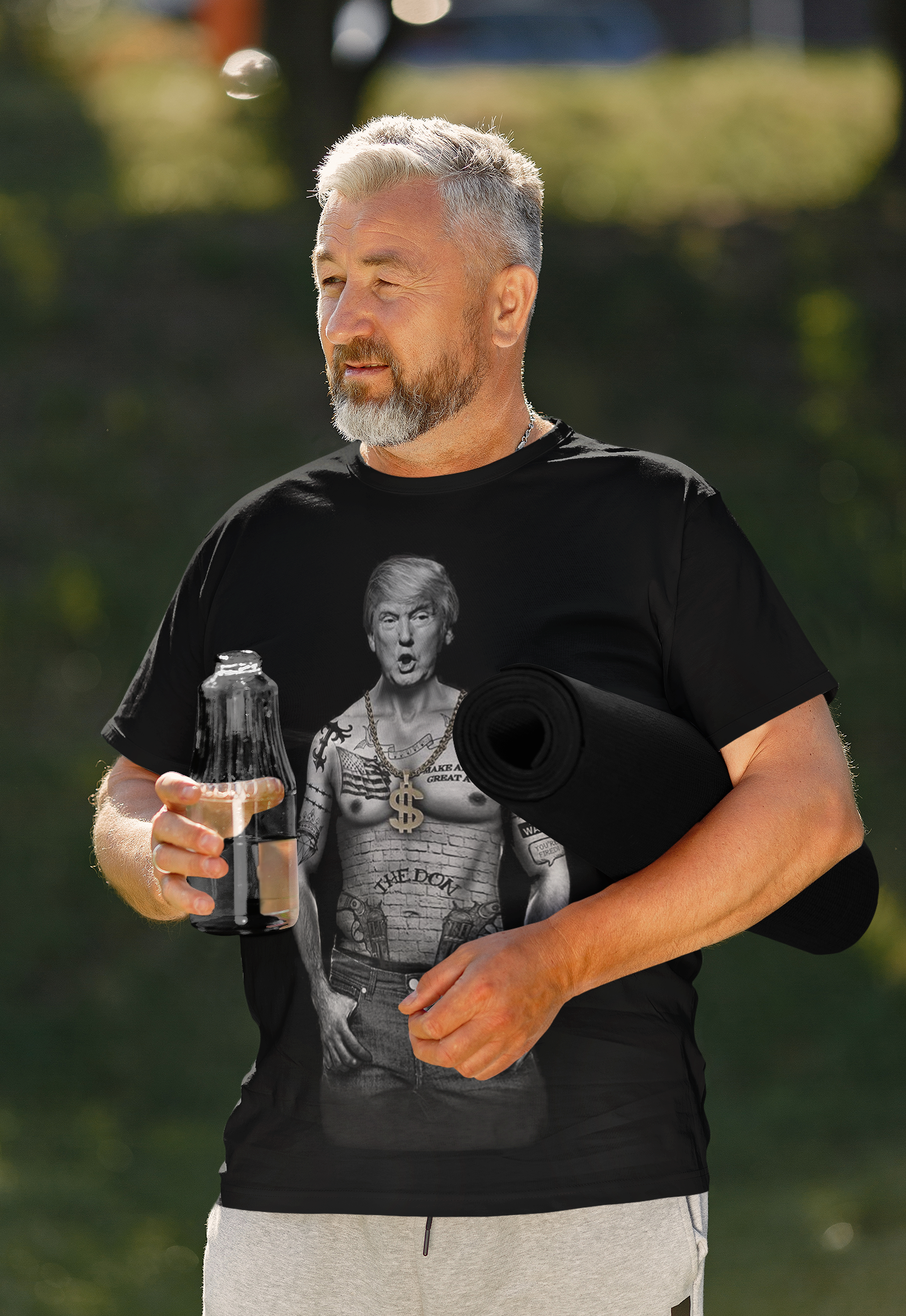 Man wearing President Trump Power Pose Art Design graphic t-shirt holding a water bottle and yoga mat outdoors
