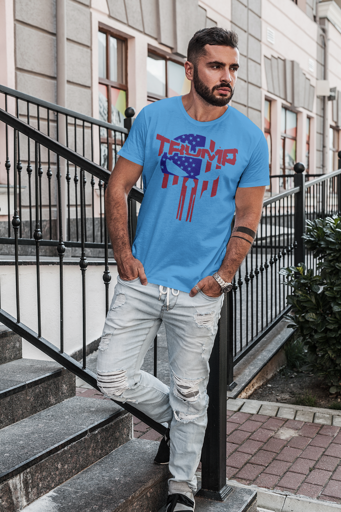 Man wearing Trump Punisher In Stars And Stripes t-shirt, standing on stairs in an outdoor setting.