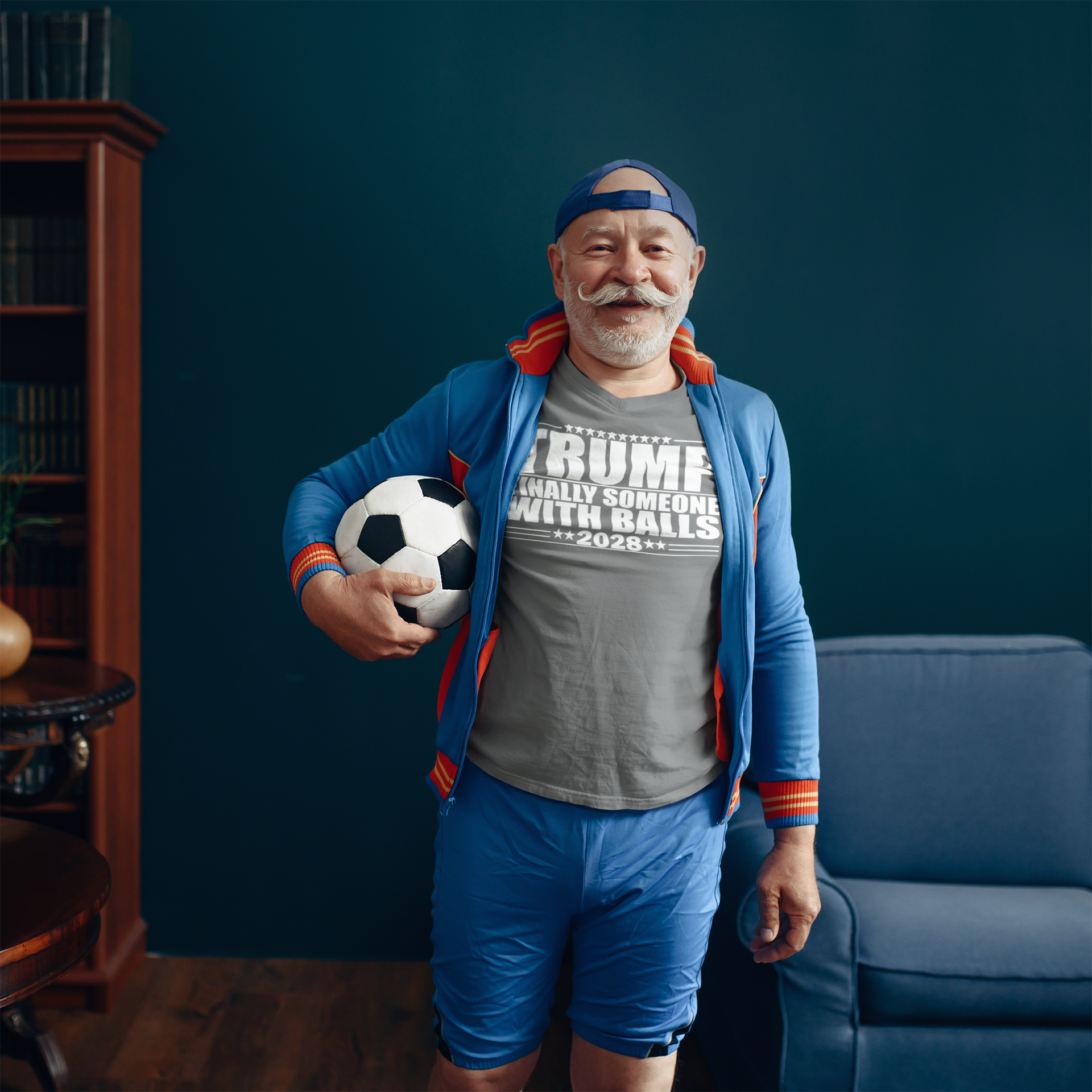 Man wearing Trump 2028 Finally Someone With Balls shirt holding a soccer ball in a cozy room.