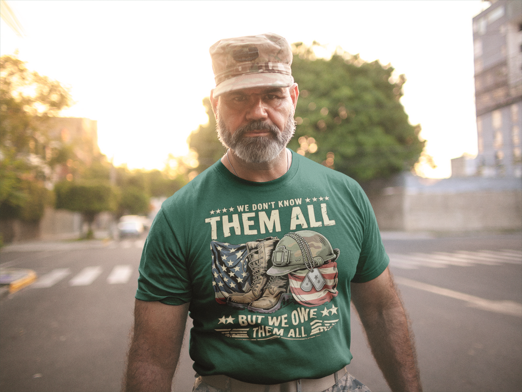 A veteran wearing a green shirt with the phrase We Don't Know Them All But We Owe Them All, supporting national ideals.