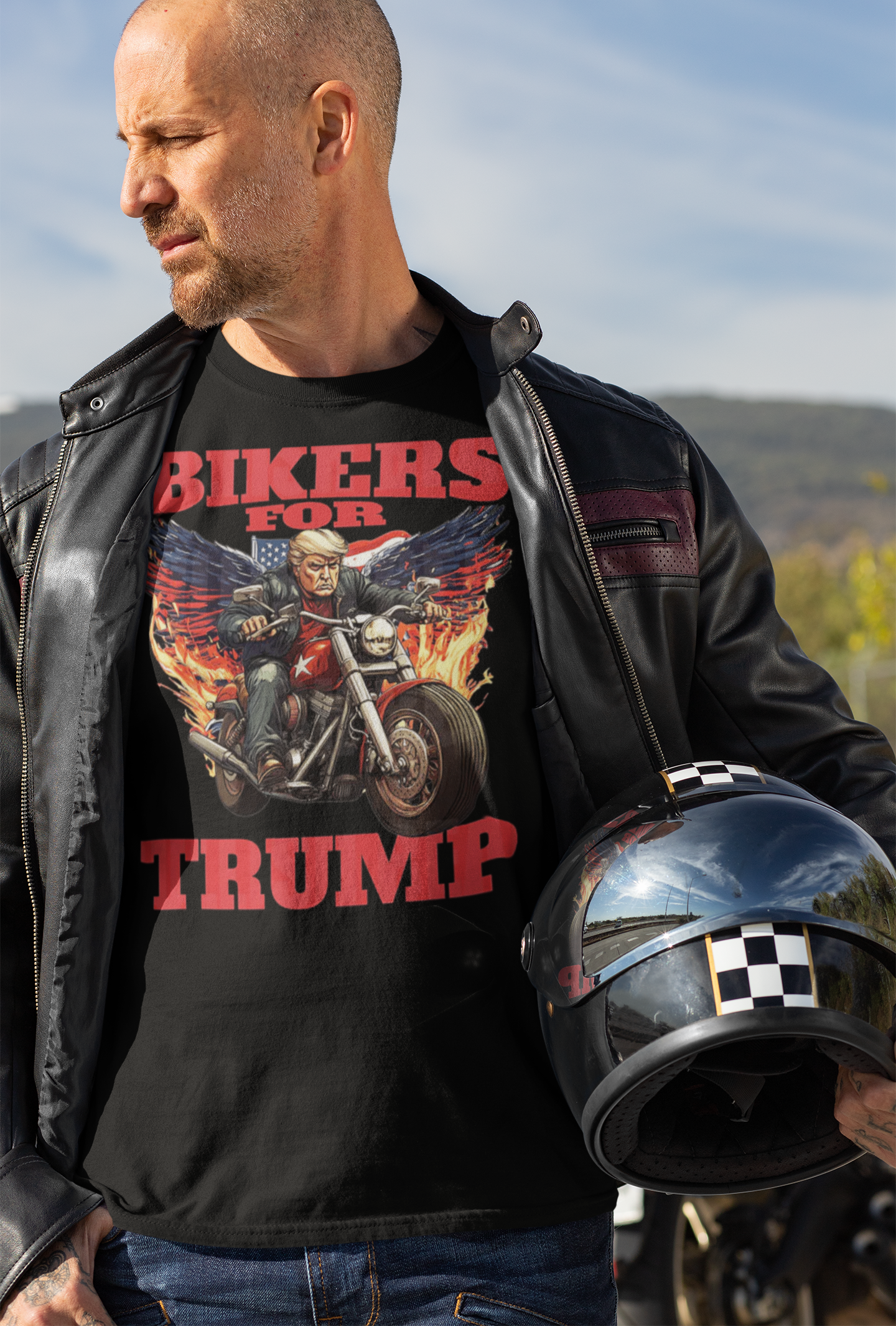 Man wearing a Bikers For Trump Graphic Design t-shirt, standing with a motorcycle helmet in hand.