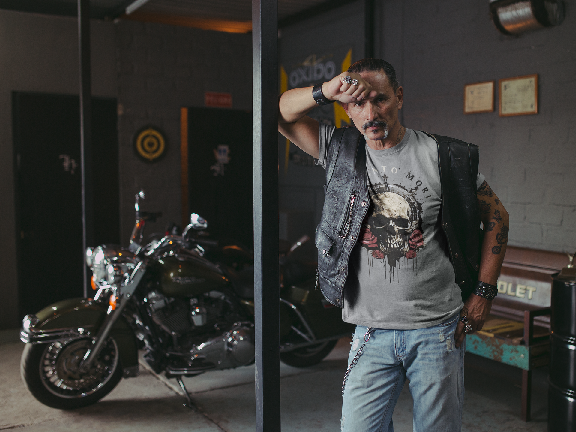 Man wearing Memento Mori Life Motto Apparel graphic tee in a garage with a motorcycle.