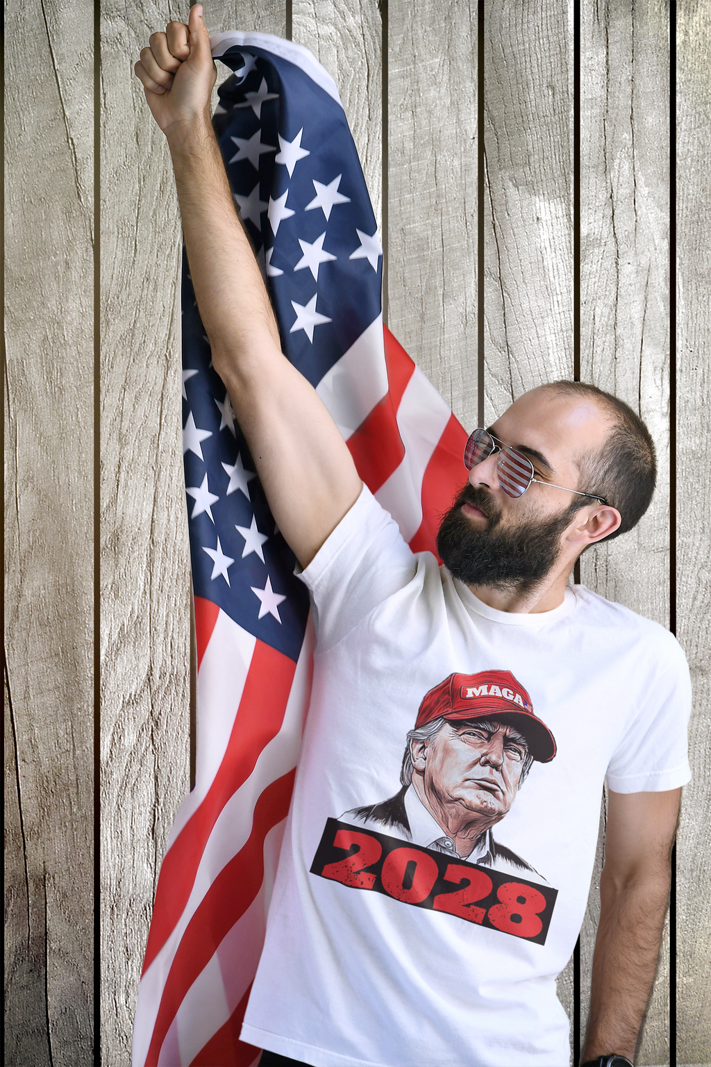 Man proudly wearing Trump Maga 2028 Visionary Gear tee, raising fist with American flag in background.