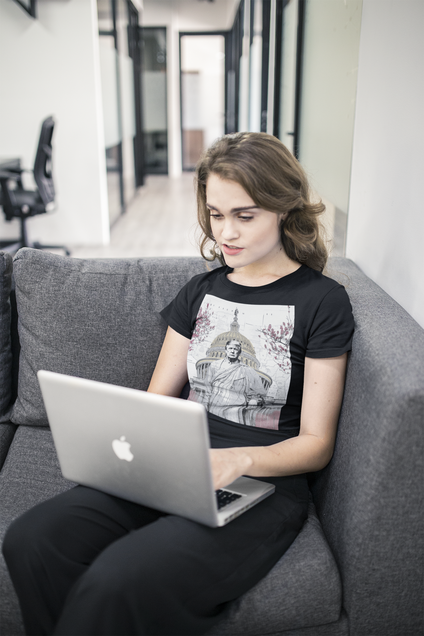 Woman wearing Trump Wearing Roman Toga Design graphic tee sitting on a couch working on a laptop.