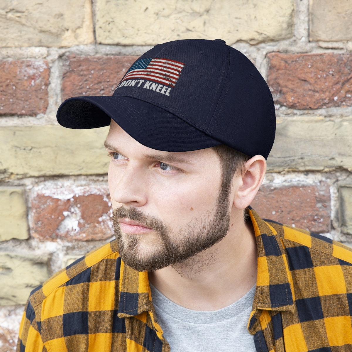 I Don't Kneel American Flag Twill Cap being worn by a man with a beard and a plaid shirt.