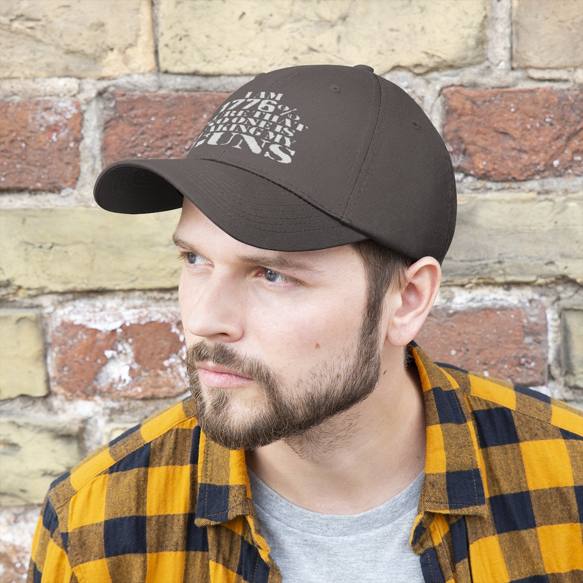 I Am 1776 Sure That No One Is Taking My Guns Twill Cap worn by a man in casual attire against a brick wall.