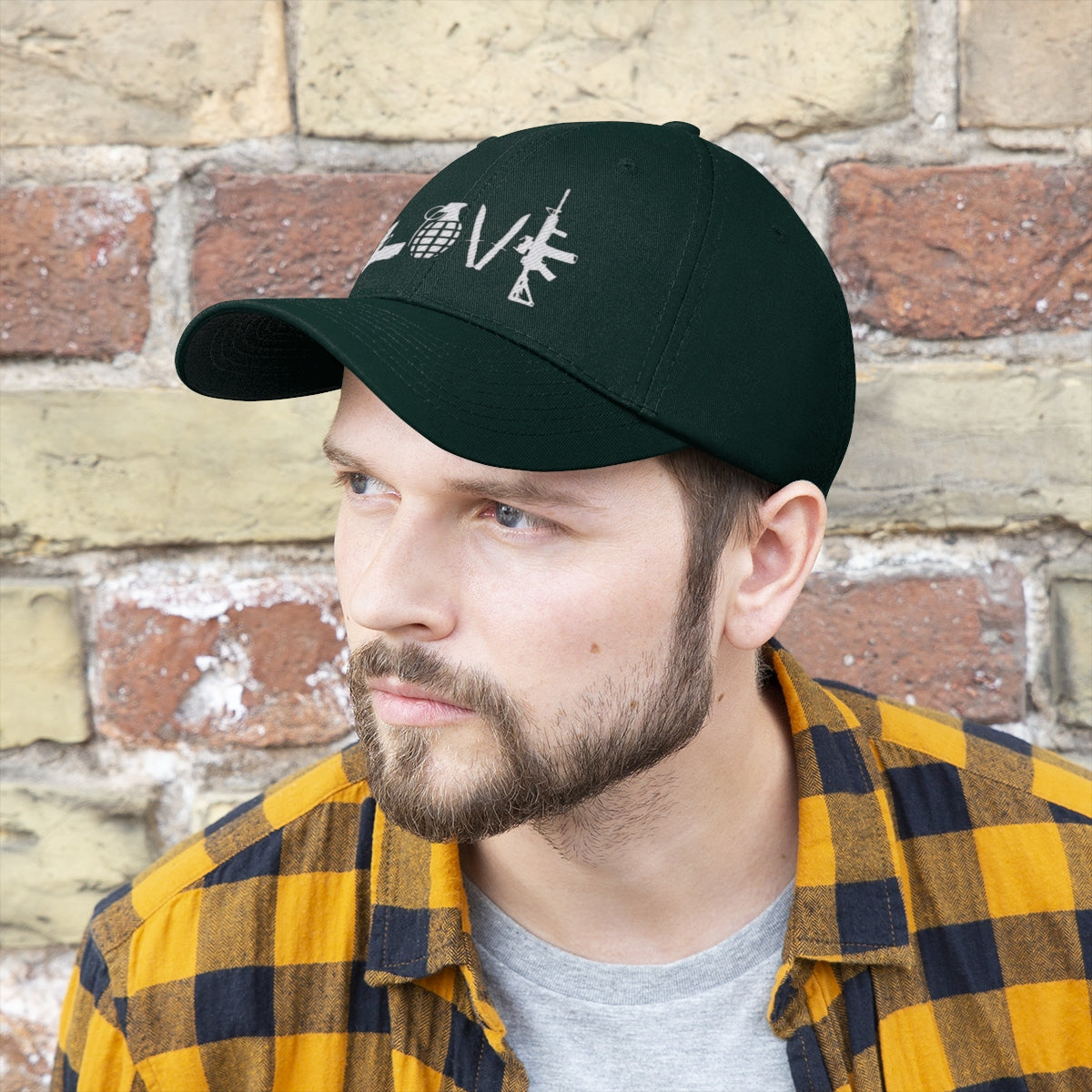 Love Combat Inspired Street Style Twill Cap worn by man with beard and plaid shirt against brick wall.