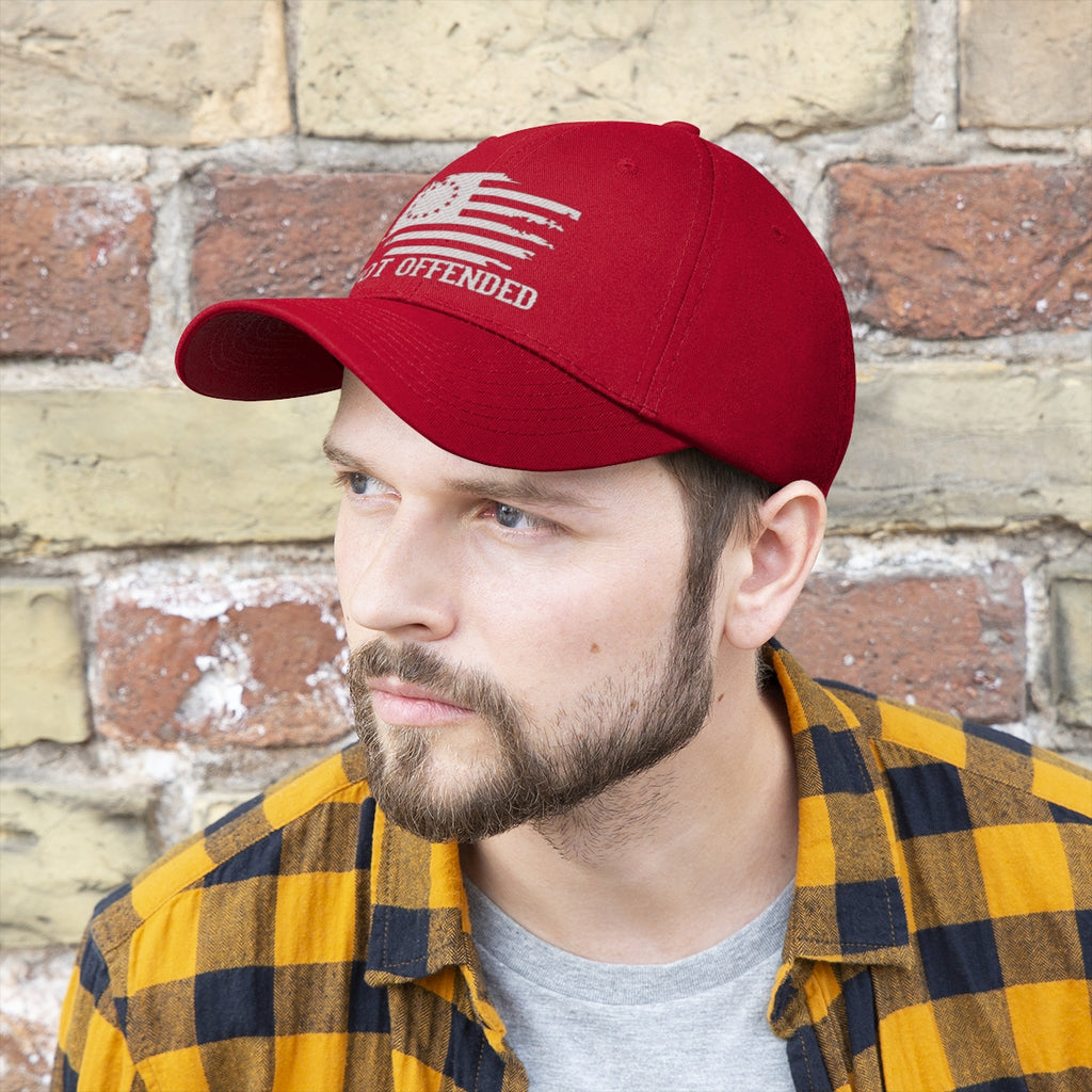 Man wearing an Embroidered Not Offended Adjustable Twill Cap against a brick wall, showcasing bold statement design.